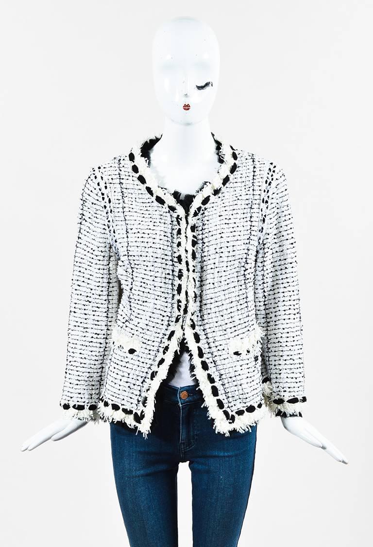 Black and white cotton blend tweed long sleeve jacket from Chanel circa Spring 2005 features black sequin embellishments. Black silk trim. Cream colored fringe trim. Rounded neckline. Shoulder pads. Concealed hook and eyes down the front for