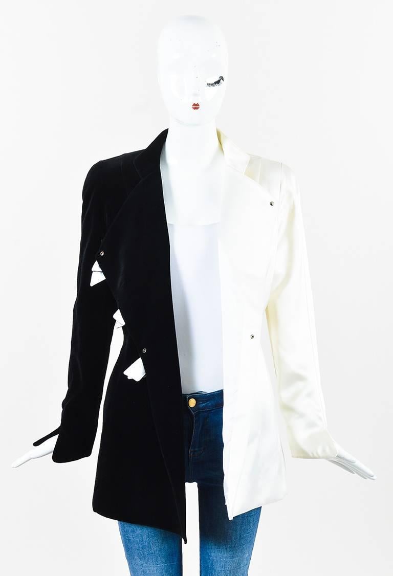 Fitted jacket. One side is a cotton velvet textile; other side a satin textile. Long sleeves. High collar. Hits at hips. Padded shoulders. Front bow detail. Hidden front snap button closure. Lined.

Size: 38
Color: Black,Cream,
Made in: