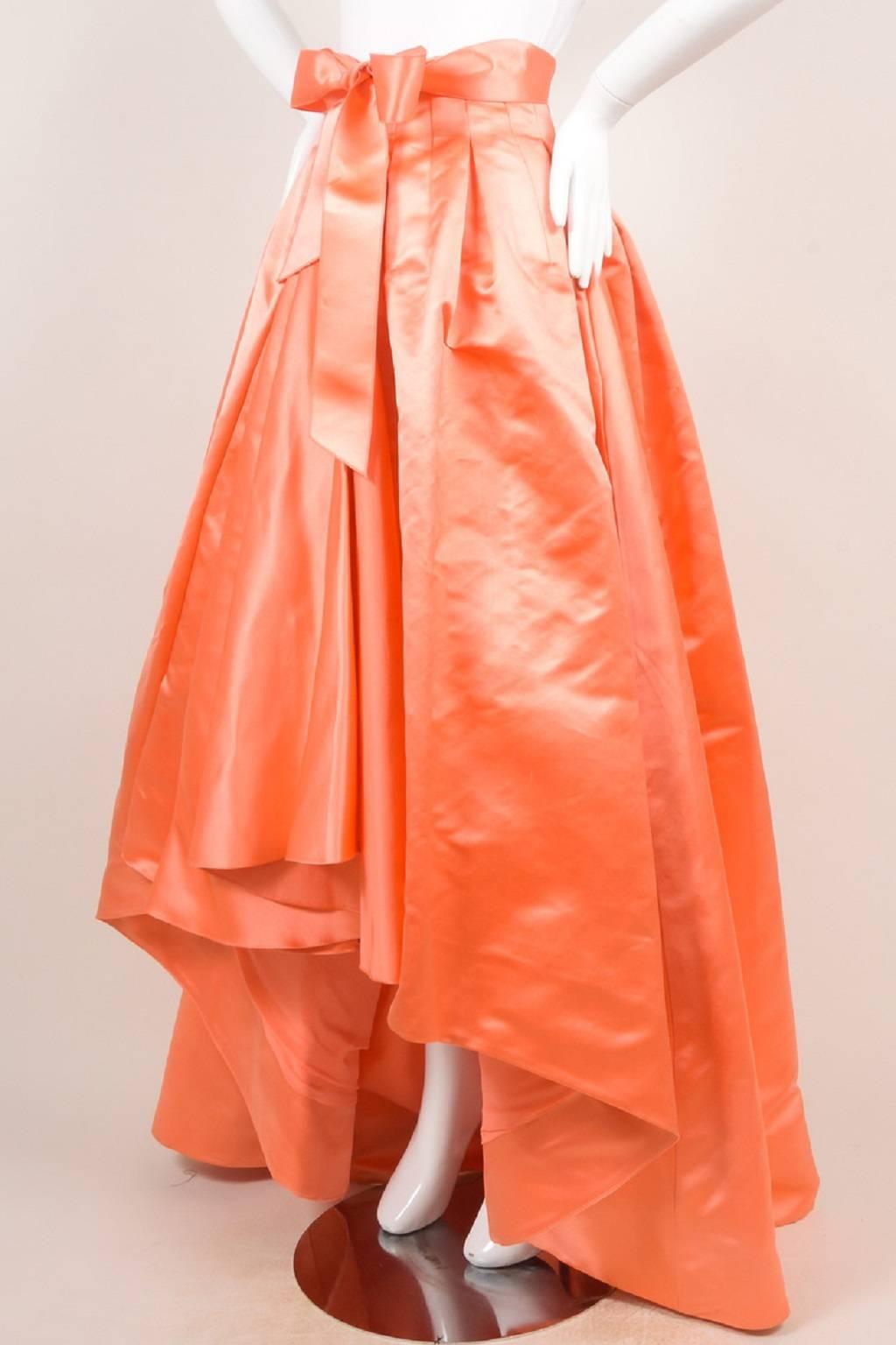 Ball skirt from Pre-Fall 2013 Collection. As seen on Jennifer Lopez. Coral silk. Pleated waist. High Low hemline. Ties at front waist. Back zipper with hook and eye closure. Lined.

Size: 6 (US); 38 (F); 10 (GB); 42 (I) 36 (D)
Color: Orange,
Style: