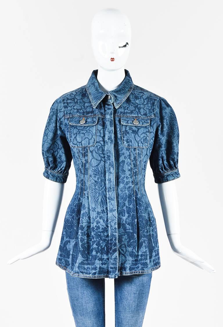Blue denim floral printed darted jacket from Chanel circa Spring 2016. Golden yellow stitching. Collar. Concealed buttons down the front for closure. Peplum cut with pleated detailing. Voluminous short sleeves have a cuff that features a silver-tone