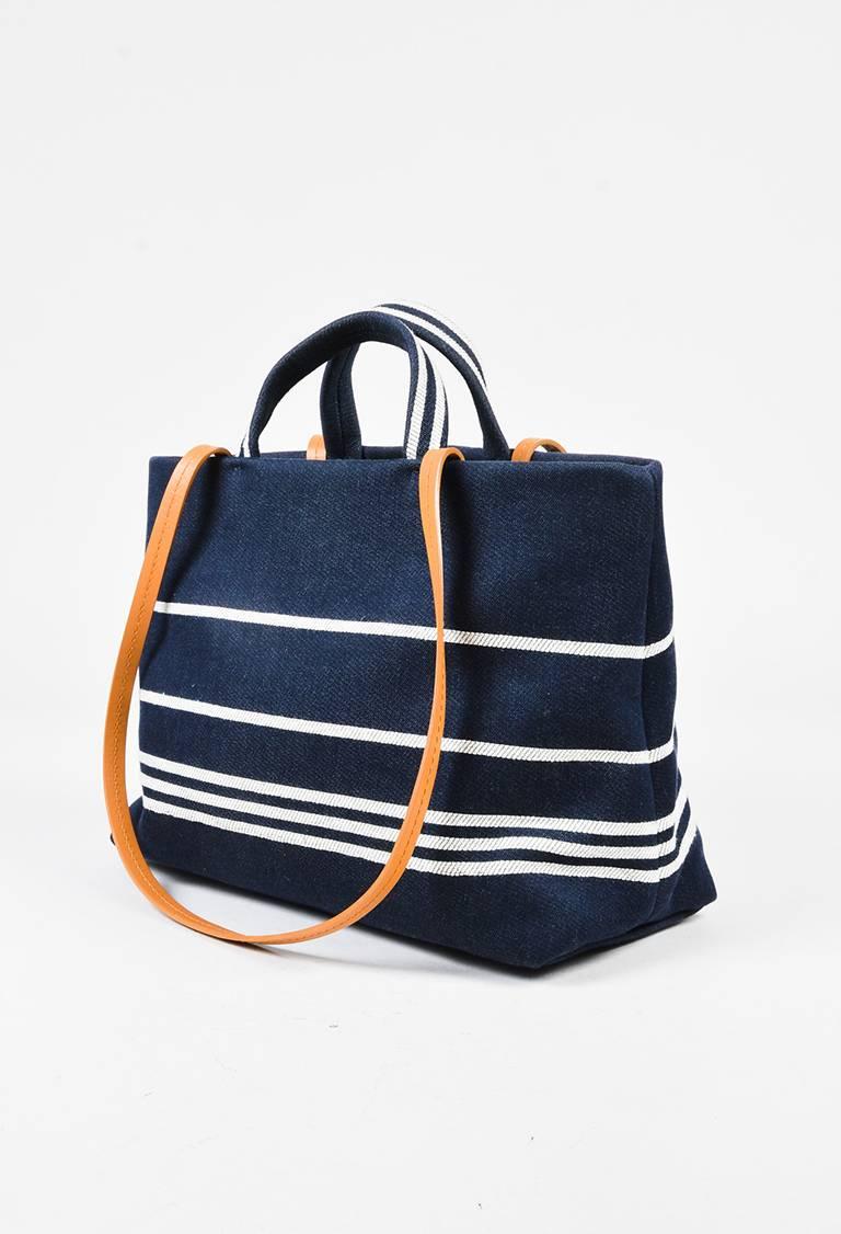 Nautical inspired Chanel denim tote circa 2014-2015. Striated stripes with 'CC' logo. Smooth leather trimmings. Flat top handle. Attached leather shoulder straps. Studded feet. Open top. Interior zip compartment. Interior strap with clasp. Interior