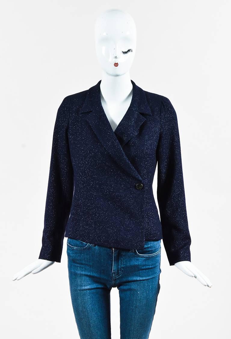 Navy blue wool blend glitter tweed long sleeve blazer jacket from Chanel circa 2000. Collar and lapels. Shoulder pads. Single button closure at the ends of the sleeves. Two buttons at lower front for closure. Slit at the lower back. Chain link trim
