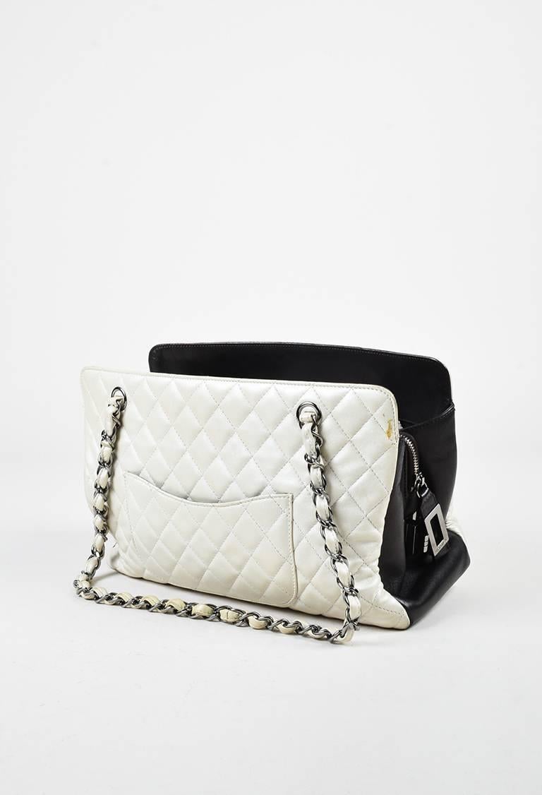 Chanel tote featuring interwoven chain-leather shoulder straps, an interlocking 'CC' detail at front, iconic quilt stitching, silver-tone hardware, an iridescent finish, a curved back pocket, and a footed seat. Interior features two open