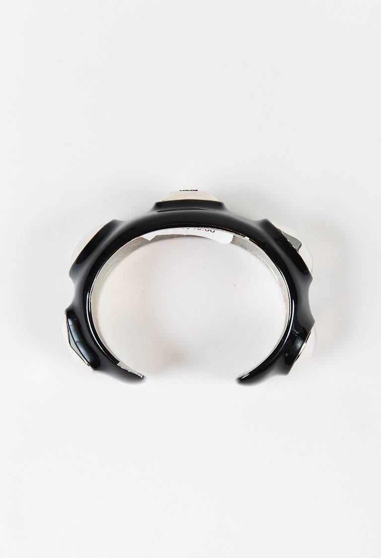 Make an edgy statement with this black enamel open cuff bracelet from Chanel circa Fall 2007; featuring large silver-tone metal stud embellishments. Signature 'CC' logo at the center. Original retail of $945. Weight : 181.4 grams. Comes with: Box,