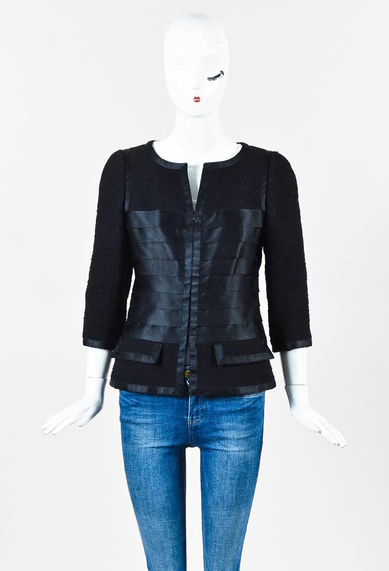 Chanel zipped tweed jacket featuring tiered satin trim, three-quarter length sleeves, and two pockets. Lined. From the autumn 2006 collection.

Size: 40 (FR)
Color: Black,
Made in: France
Fabric Content: Exterior: Wool, Nylon; Lining: