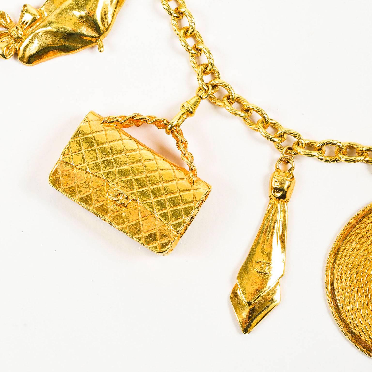 Highly collectible, vintage Chanel statement necklace. This over-the-top piece features iconic Chanel elements. Gold tone metal. Short, textured rolo chain. Dangling charms include a feminine bow, Mademoiselle Chanel, a woven sun hat, 'CC' logo