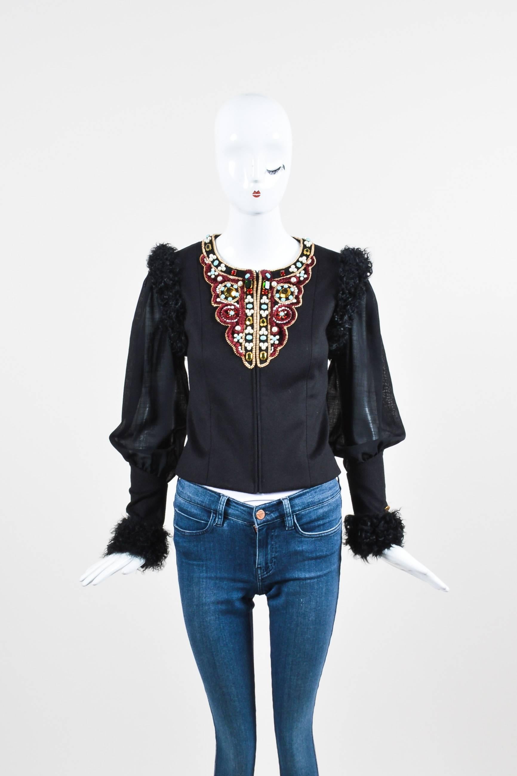 Make a bold and elegant statement in this embellished jacket by Chanel. Soft and warm cashmere body with wool panels at the sleeves and lamb fur trim throughout. Multicolored gems and faux pearls at the front neckline. Pops of burgundy red,