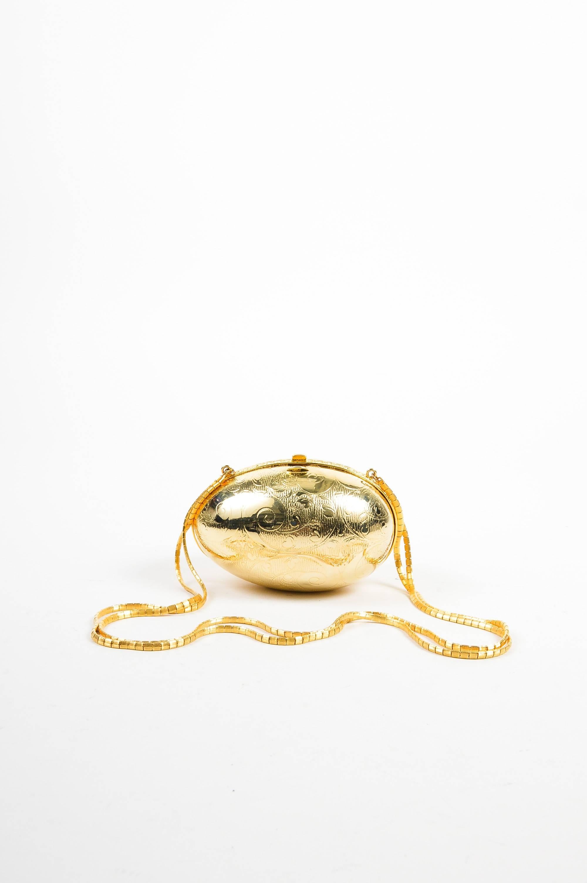 Get the Midas touch with this gold-tone, metallic purse by Judith Leiber. This egg-shaped bag is eye-catching and will be sure to make conversation at your next event. Etched exterior with a filigree design. Hinged opening with a push lock closure.