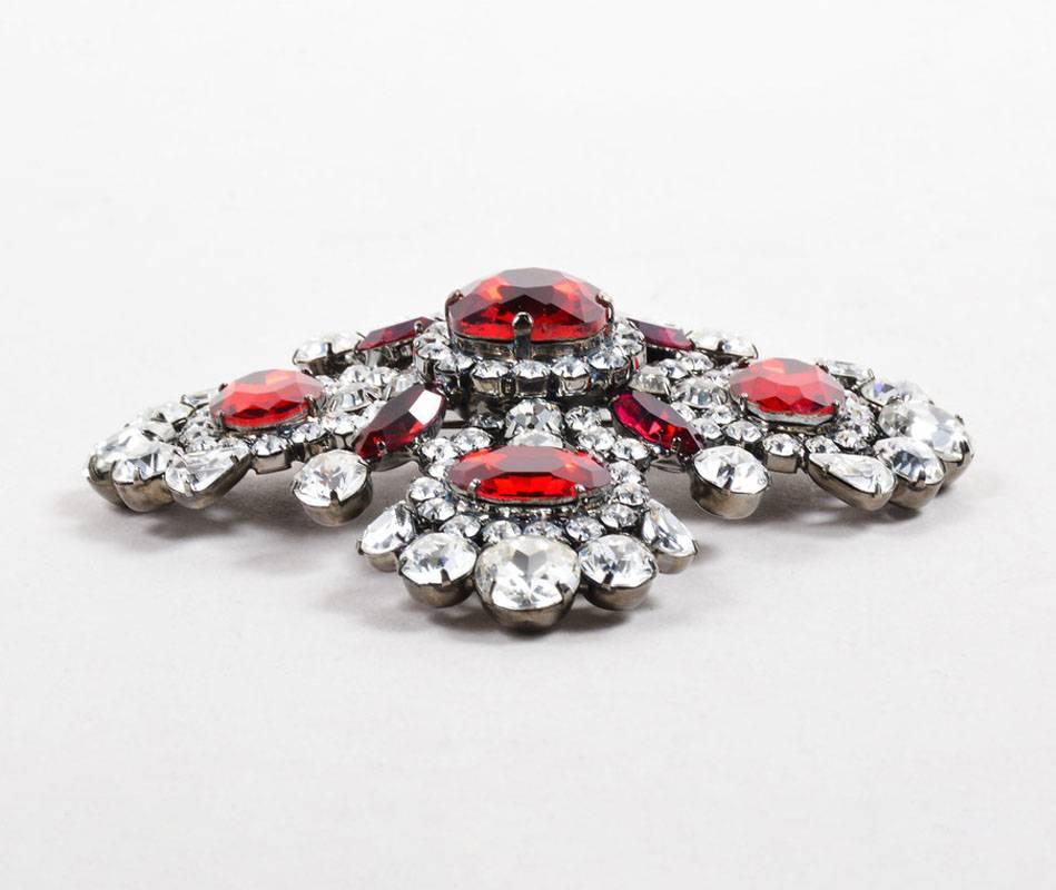 Elegant brooch to make a statement to an outfit. Silver-tone metal base. Clear bejeweled embellishment with contrast red gemstones. Back c-clasp closure.

Condition:
Pre-owned. This item is in good condition. Faint scuffs and slight oxidation on
