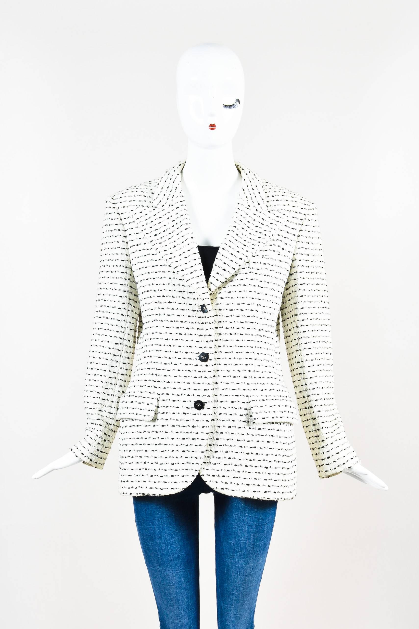 Chic jacket featuring a long silhouette, 'CC' buttons at the front and sleeve plackets, structured shoulders, front flap pockets, and a peak lapel. Single breast pocket. Silvery metallic chain trim at underside of hem. Textured knit construction.