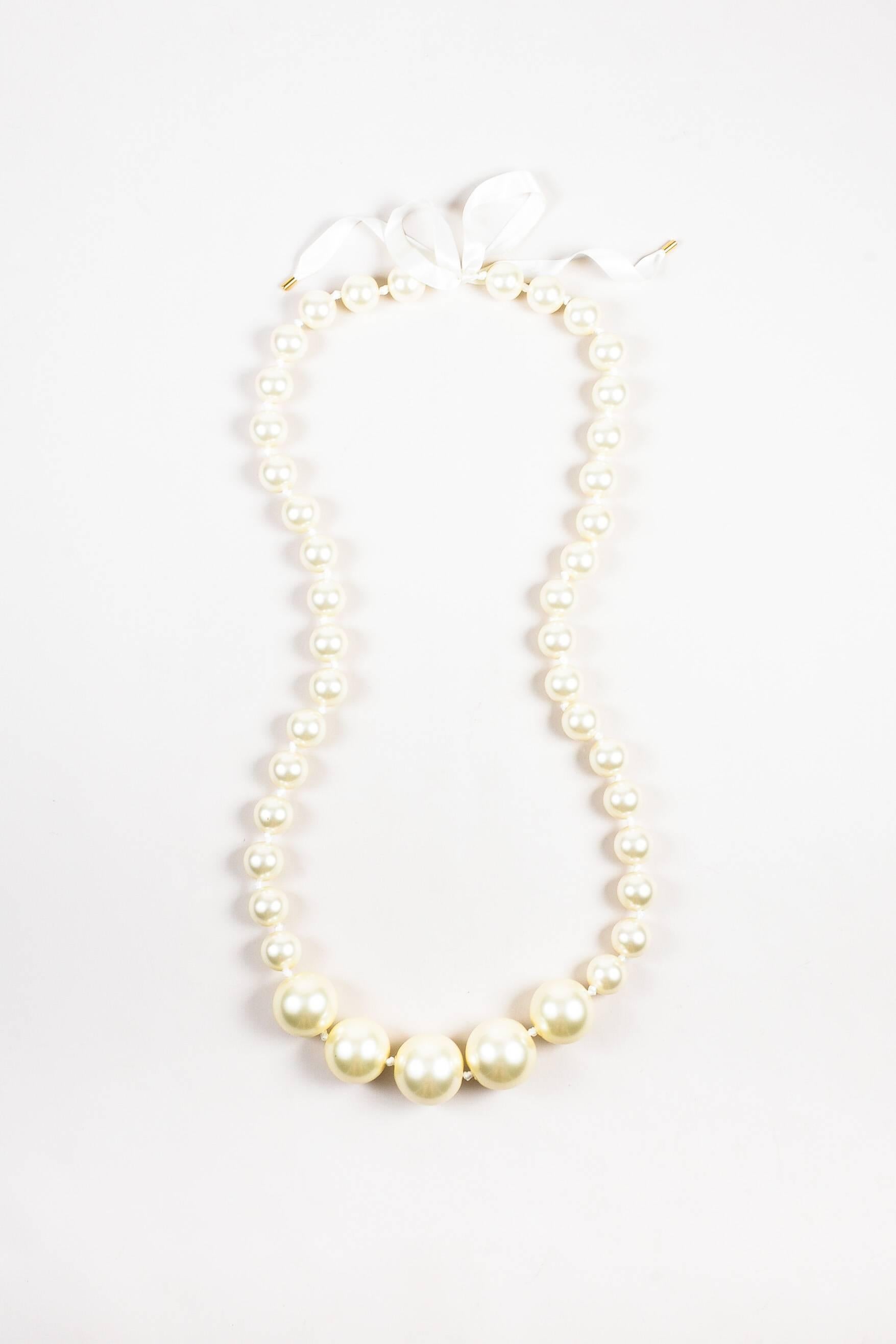 From the Louis Vuitton Fall 2006 Runway collection, this stunning statement pearl necklace features oversized, chunky faux pearl beads strung on white satin ribbon. Long length allows you to wear this single, double, or triple-layered. Self-tie