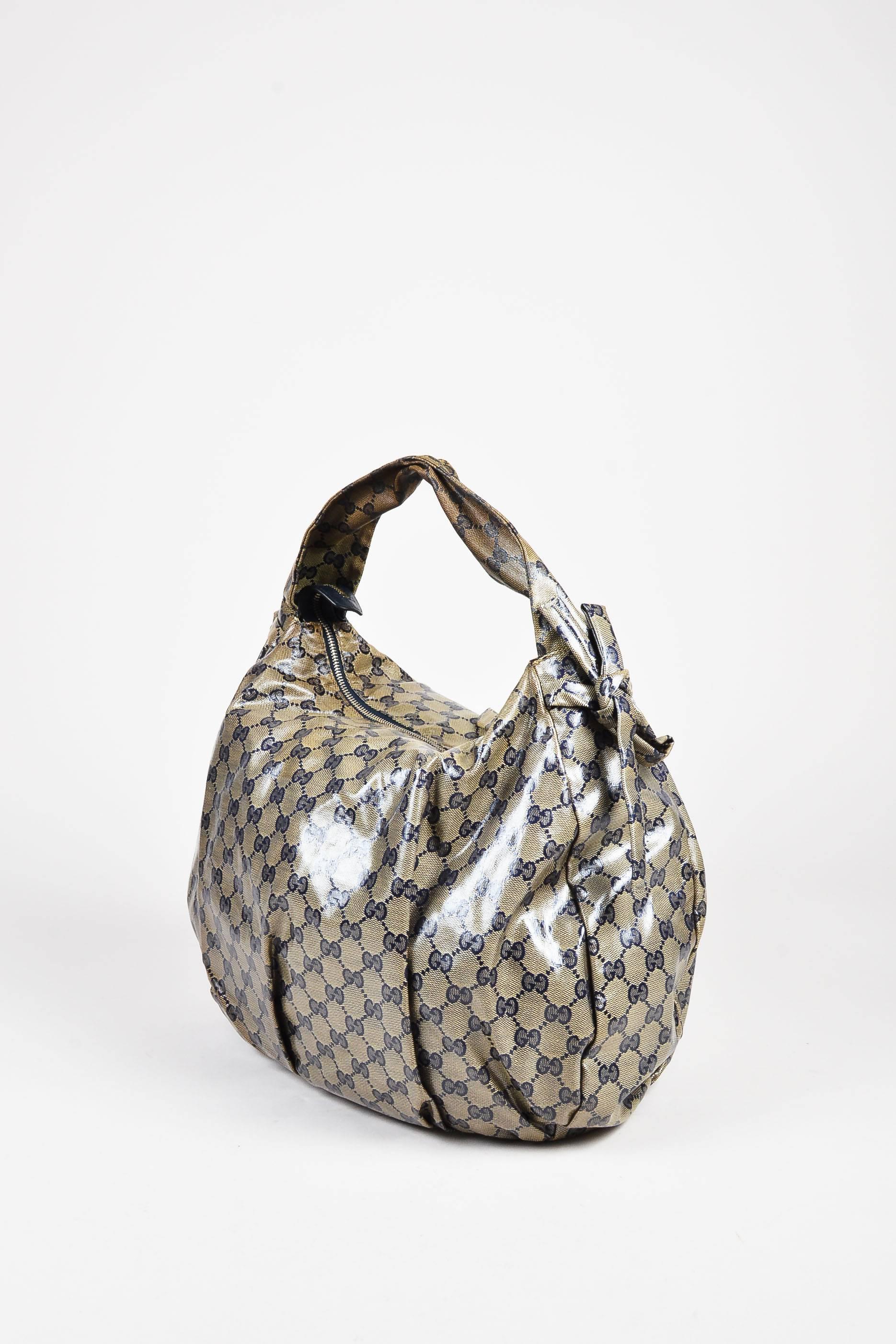 Comes in dust bag. Roomy hobo bag is constructed of slick monogram coated canvas. Metal logo plate on front. Top zip closure with tie accents at each side. Flat top strap. Serial number reads, 