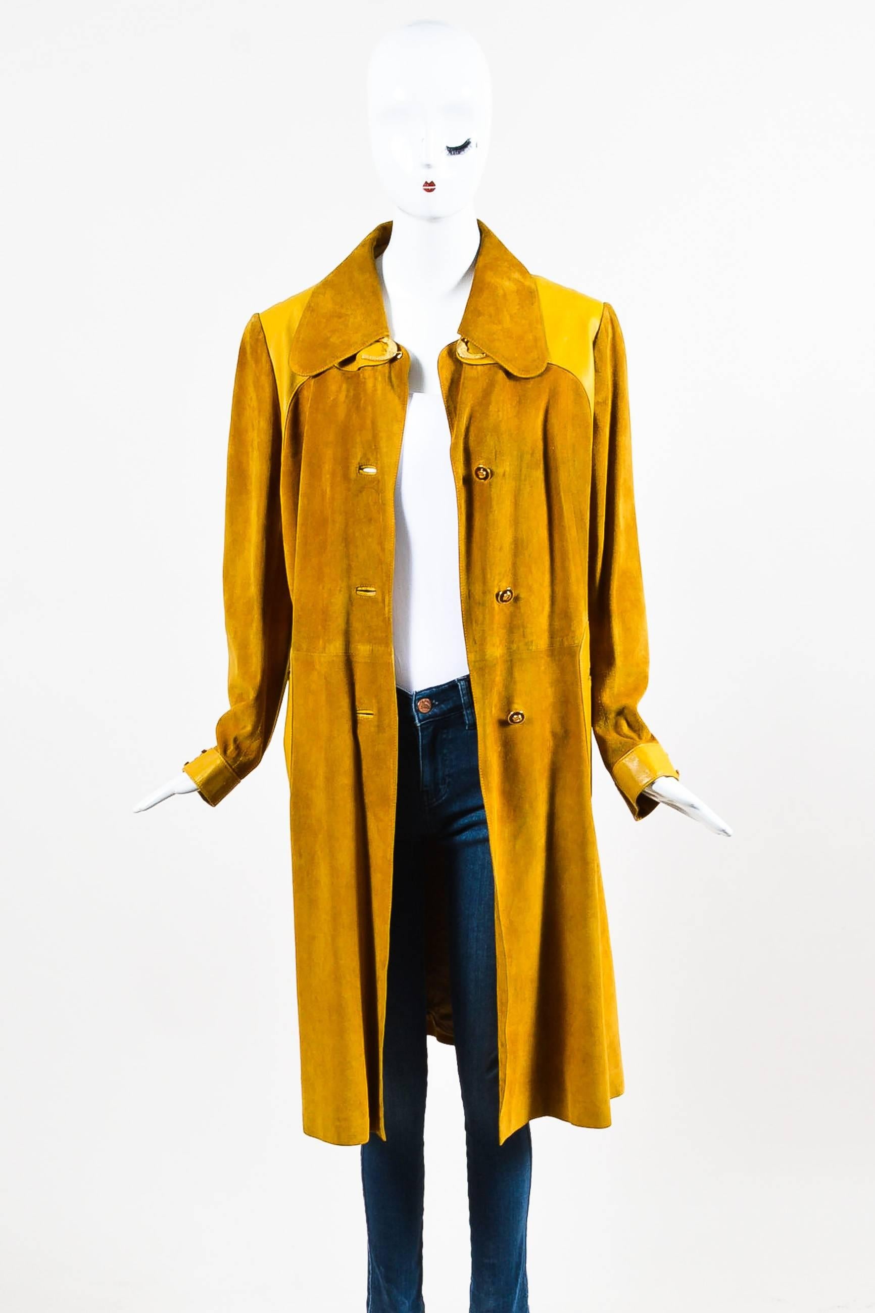 Mustard yellow suede coat with matching leather trim. Long sleeves with gold-tone horseshoe hardware. Front slit pockets. Center vent. Buttons up front. Lined.

Size: 
48 (IT)
12 (US) 

Measurements:
Total Length: 40.5"
Sleeve Length: