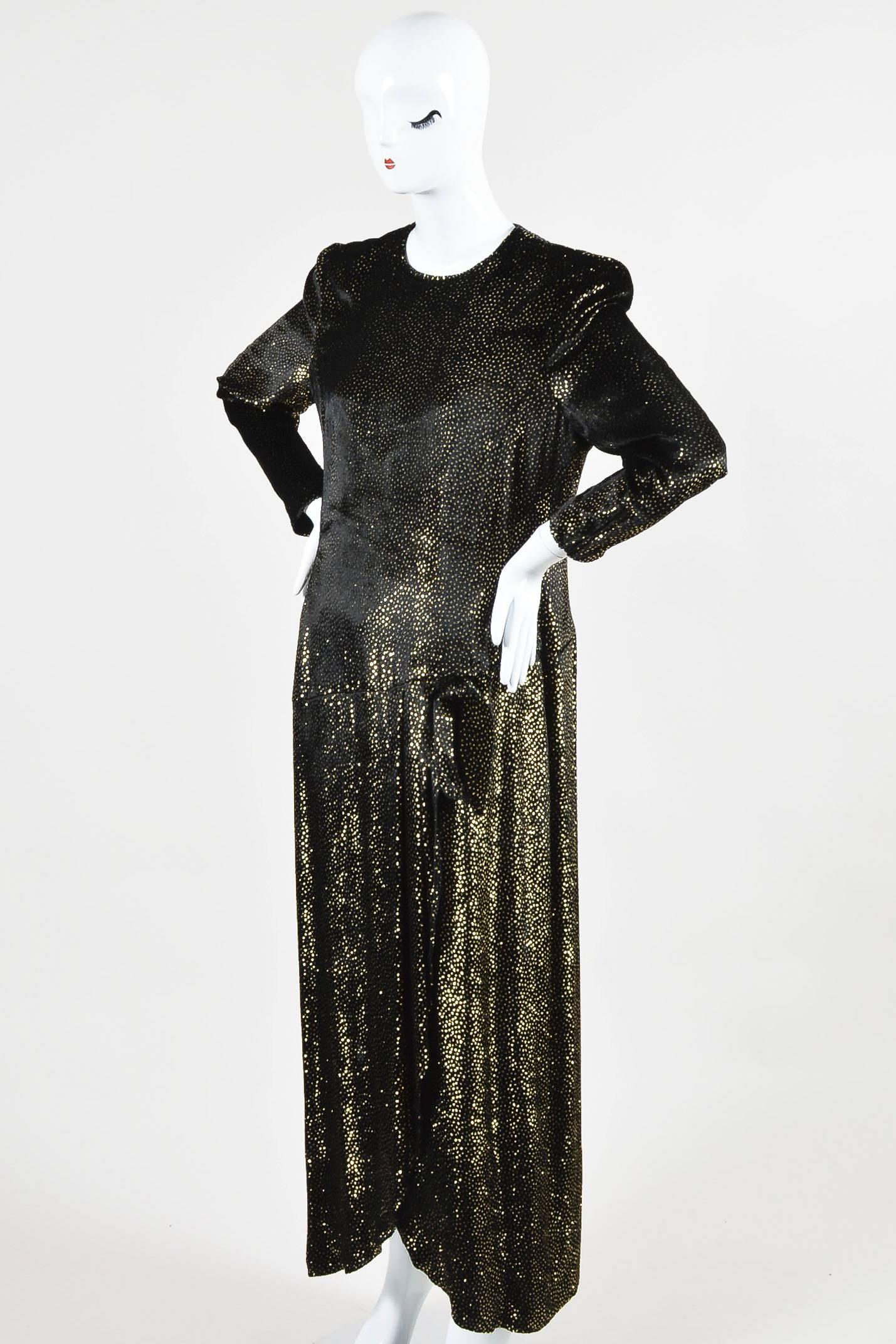 Vintage Escada dress featuring soft black velvet, metallic gold clustered sparkles, long sleeves, round neckline, bow at waist, and slit at side. Shoulder padding. Partially lined. Closes in back with hidden zipper.

Size	
42 (Germany)
 12