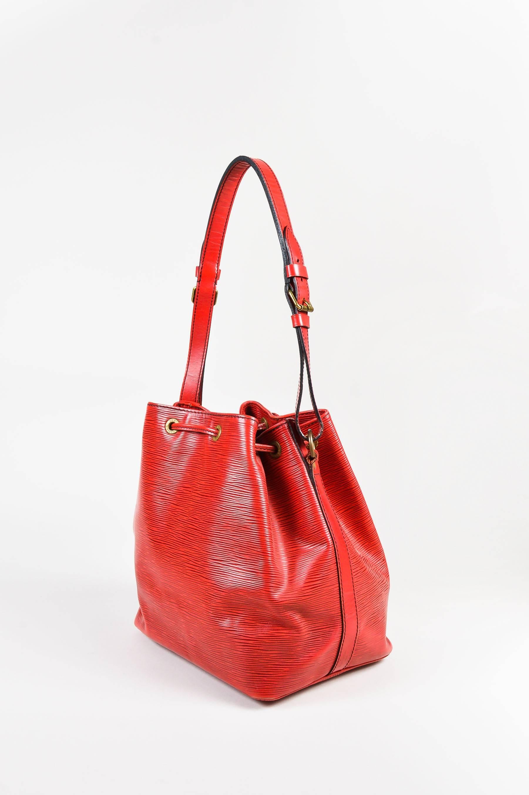 Fabric Content: Epi Leather

Item Specifics & Details: Vintage bucket bag is constructed of red epi leather. Flat shoulder strap. Drawstring top. Date code reads, "A20992". Circa 1992.

Measurements:
Strap Length: