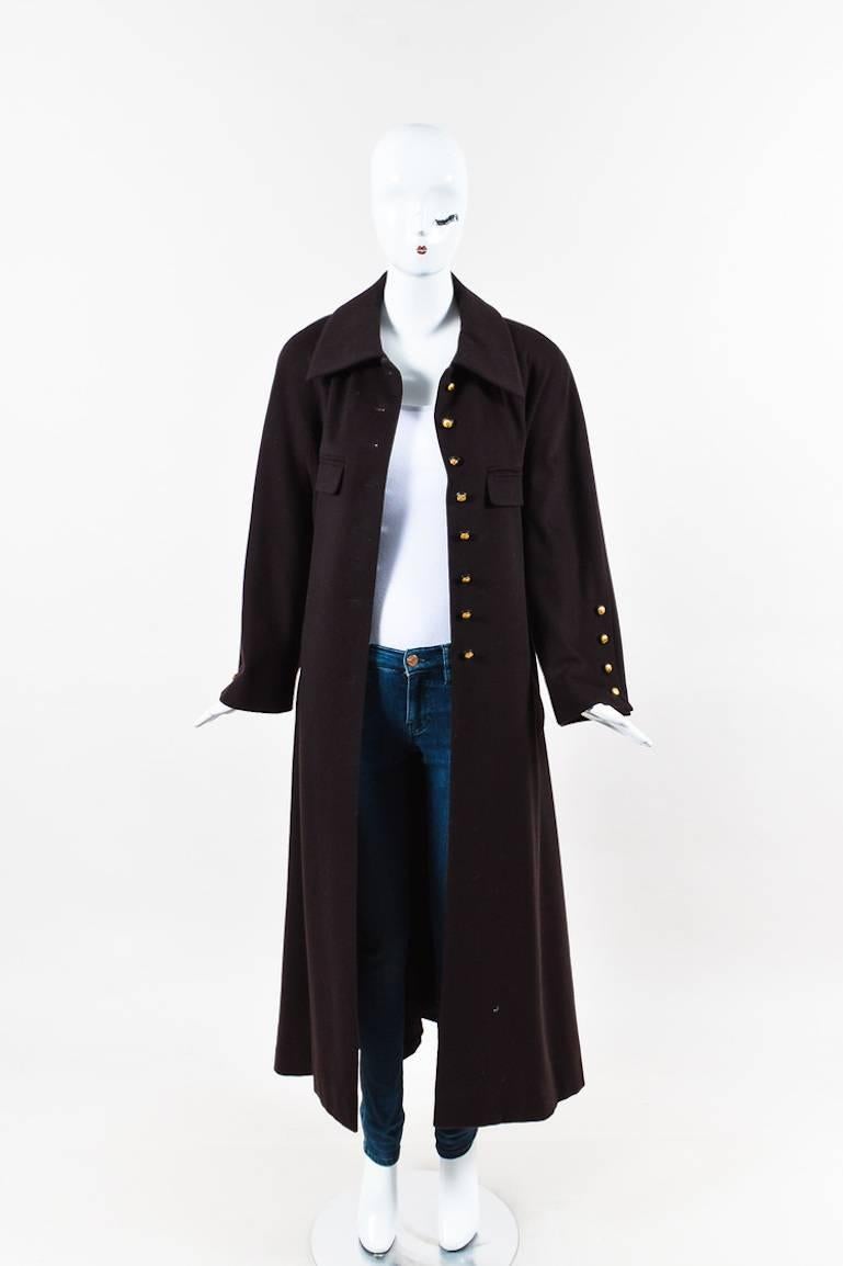 Vintage dark brown cashmere and wool long coat from Chanel Boutique. Collar and shoulder pads. Rounded neckline. Raglan cut sleeves. Gold-tone buttons down the front for closure feature an embossed 'CC' logo. Two front open pockets and two faux flap