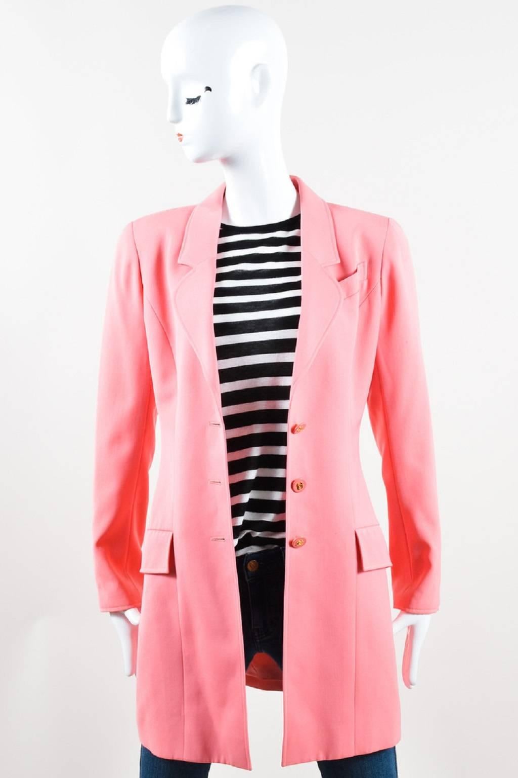 Long coral pink wool jacket secures with gold tone 'CC' buttons in front. Long sleeves have padded shoulders and matching buttons at openings. Two flap pockets on front. Lapel pocket is basted closed. Center back slit. Silk lined.

Color: