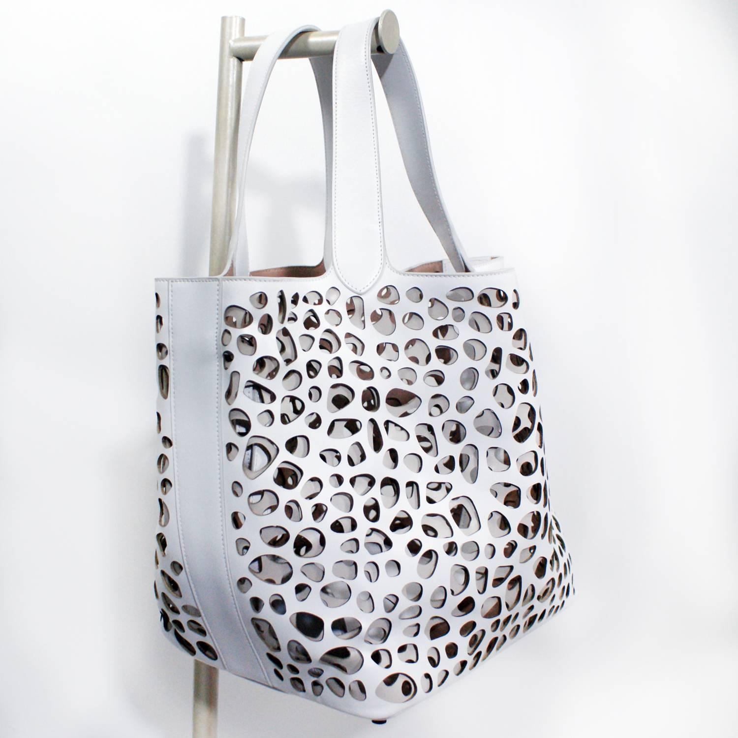 White leather cut out design
Taupe interior leather
Two tote handles
zip clutch inside 
