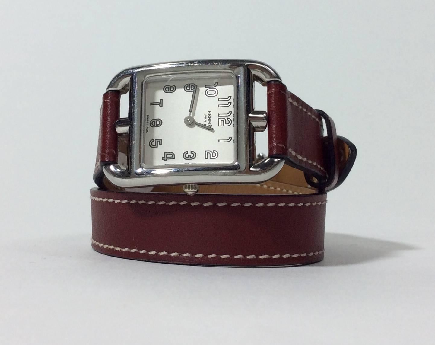 Brown Leather Wraparound Watch
White face with silver retro numbers
Brown leather band adjustable from 11.5-13 inches 
0.5 inches thick
Hermes logo engraved on back of face