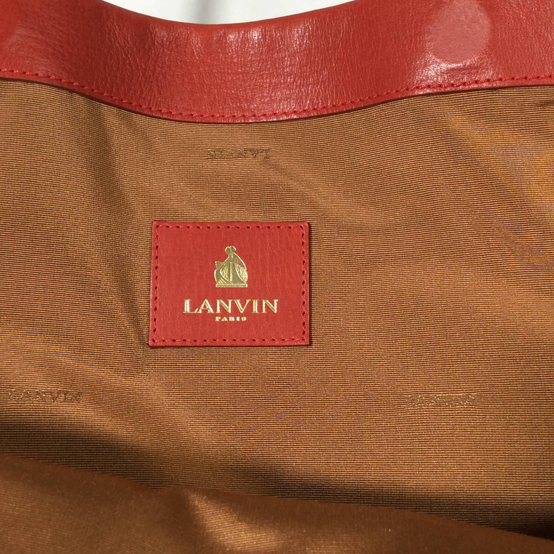 Lanvin Red Leather Tote with Gold Hardware
Two external compartments
No internal pockets
6.5 inch strap drop
Leather exterior with woven taupe lining
Includes standing hardware on base of bag