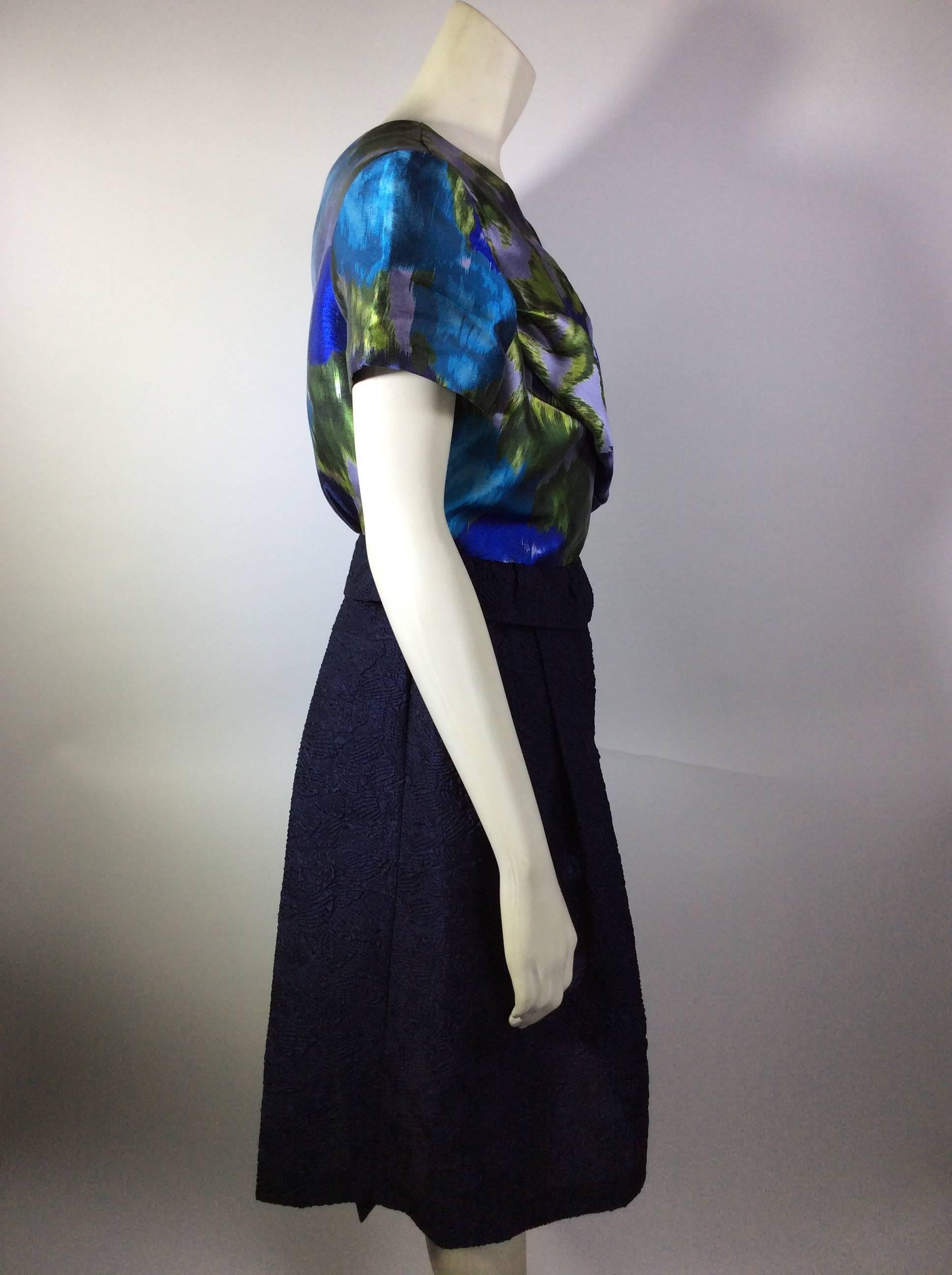 Floral Print and Navy Cross Back A-line Dress
Ruched detail on bodice
Crossed back with hook and eye closure on left side of dress
Folded over navy belt detail on skirt
Features cap sleeves
Size 12
