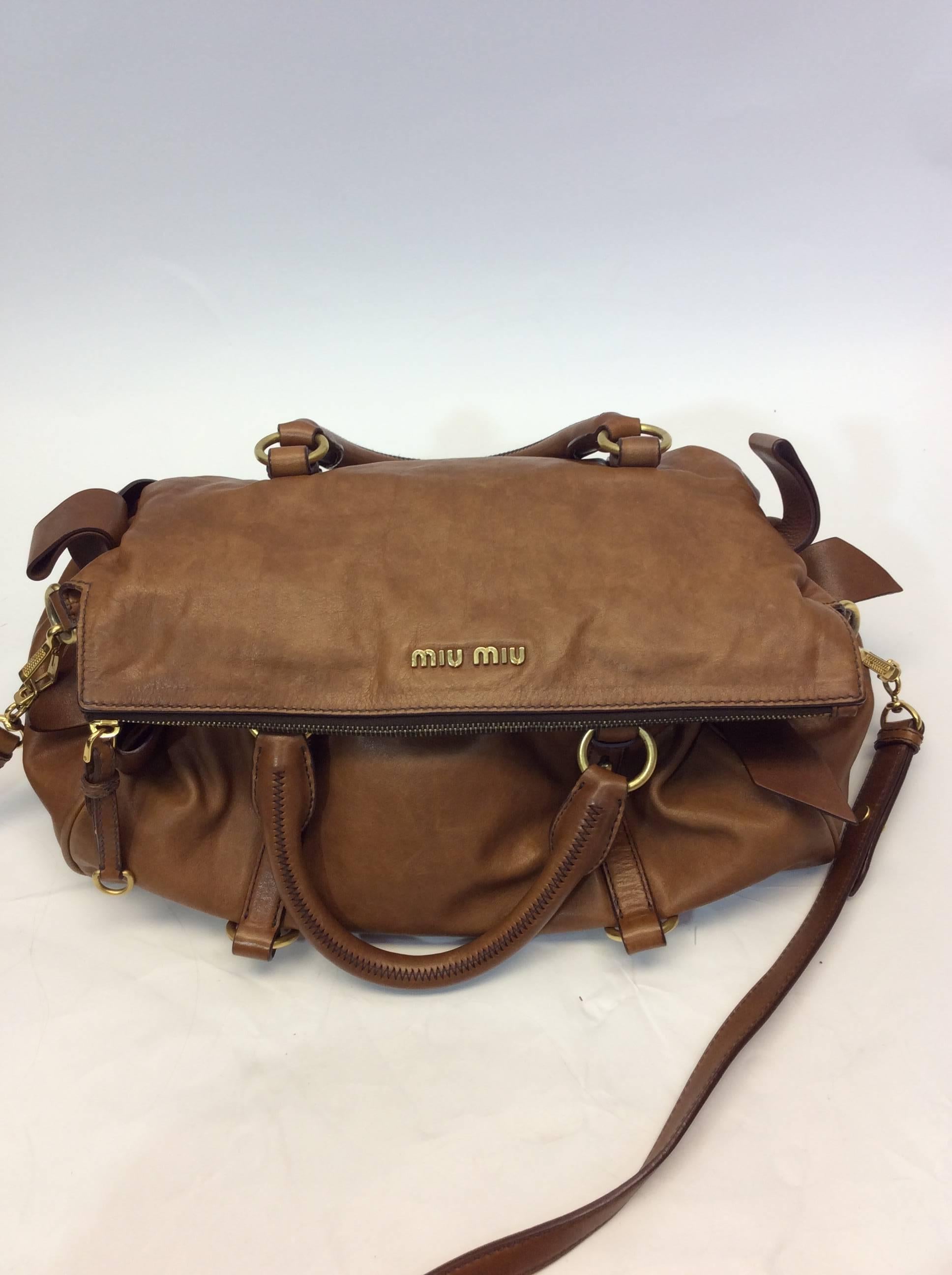 Brown Vitello Lux Bow Bag
14.5 inches wide, 10 inches tall, 7.5 inches deep
3 inch strap drop with 40 inch removable crossbody strap
Bow details on bag sides
Top zipper closure
Includes one interior zipped pocket
Leather exterior, cloth lining