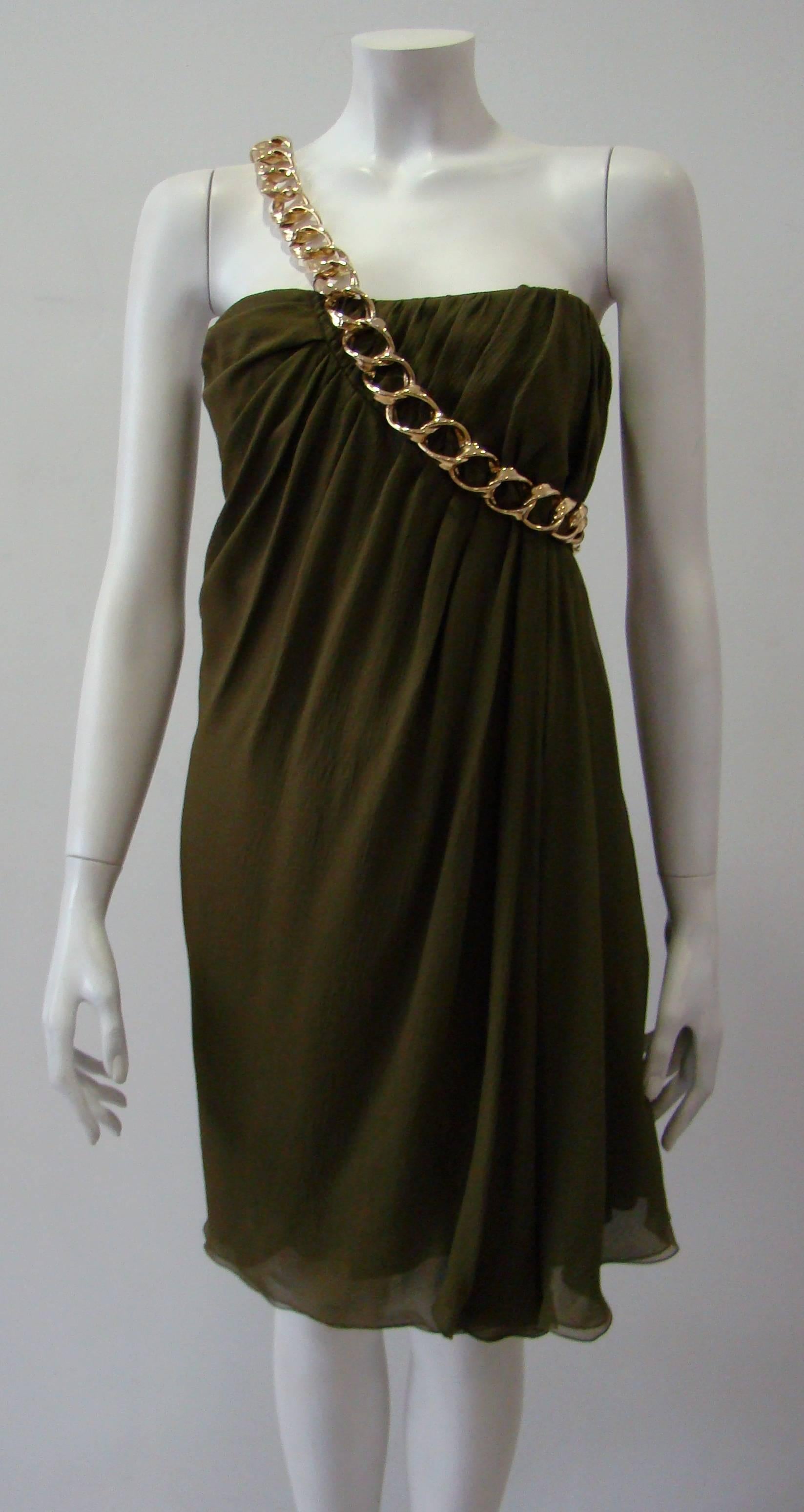 Pierre Balmain Cocktail Dress. An Olive Green Ruffle Dress, 100%Silk Featuring A Gold Chain Which Hugs One Arm. An Easy And Beatiful Choice For Evening Events.