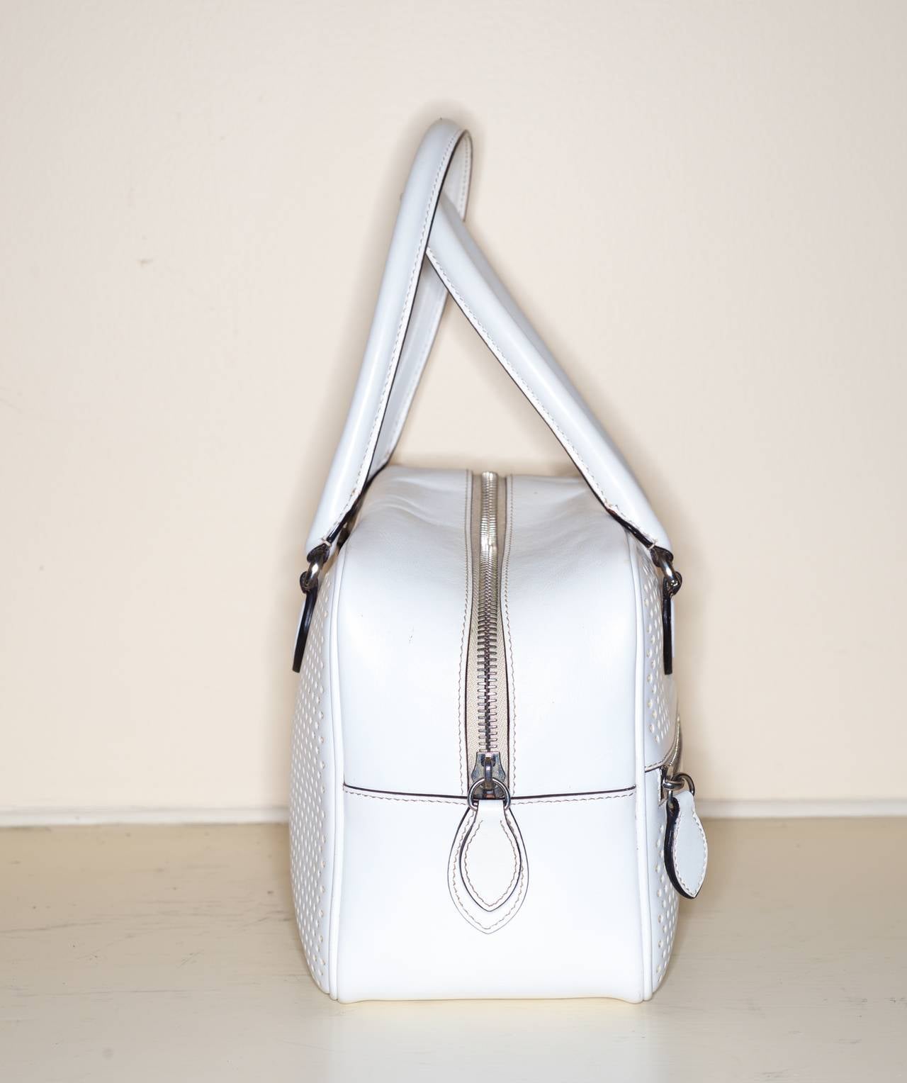 This Alaia white perforated leather tote is spacious and light .  

Exterior zipper pocket, Interior has a drawstring leather pouch and a detachable mirror.

Measurements: 
nearly 11