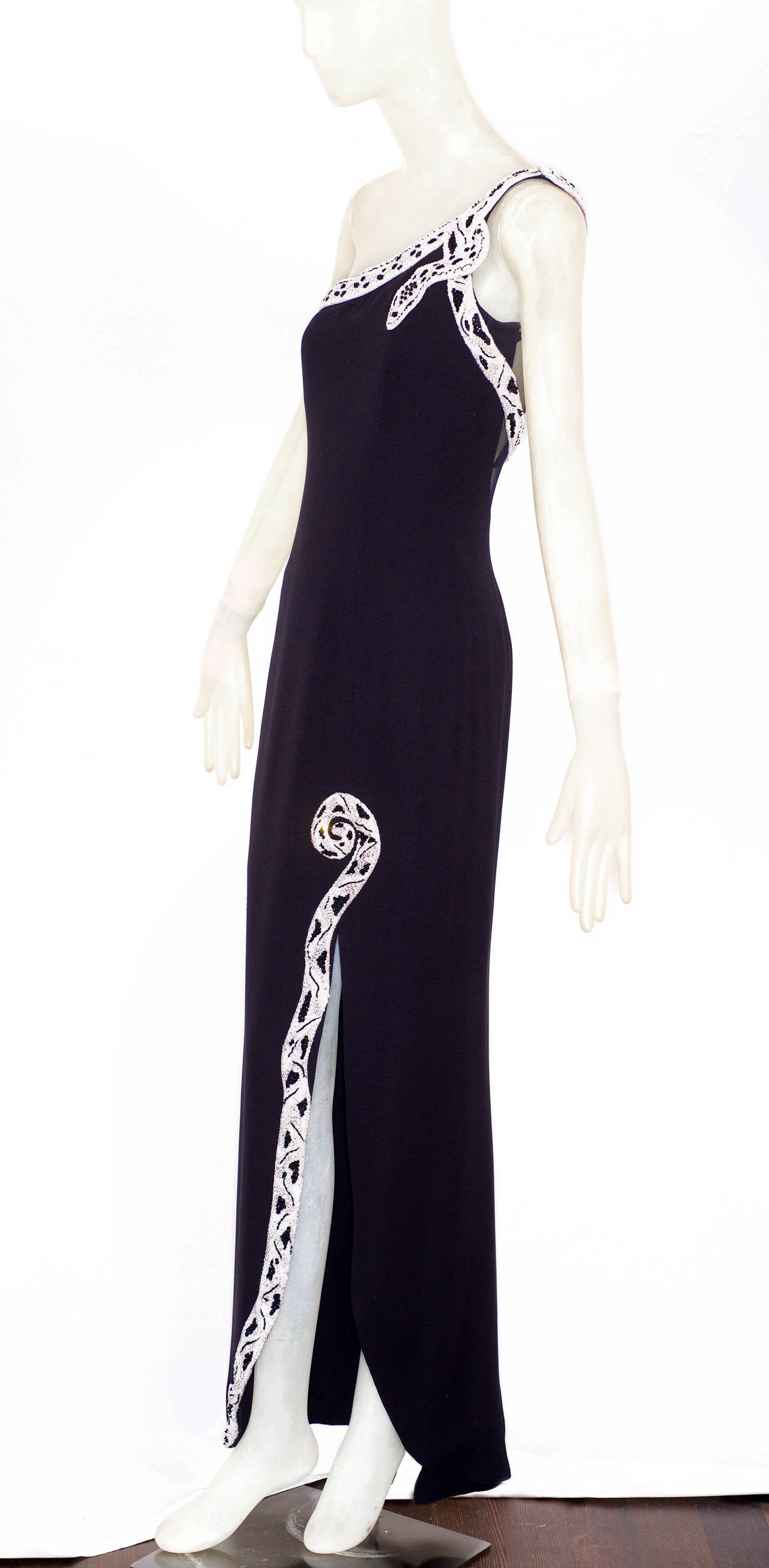 An extraordinary example of Italian glamour by Valentino.  Circa 1970s four ply silk crepe gown, with Goddess style one shoulder strap adorned with a bijoux-embroidered python.  The python wraps itself around the front bodice to the back.  The back