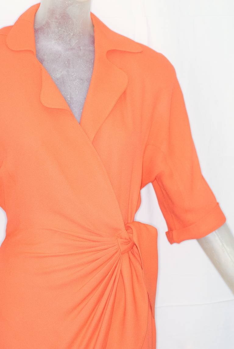 A bold Thierry Mugler wrap dress in a beautiful shade of coral, cut to flatter the body in the way only Mugler could.  With waist defining ties and asymmetric hem, it is classic Mugler glamour.

No size label but will fit a modern size