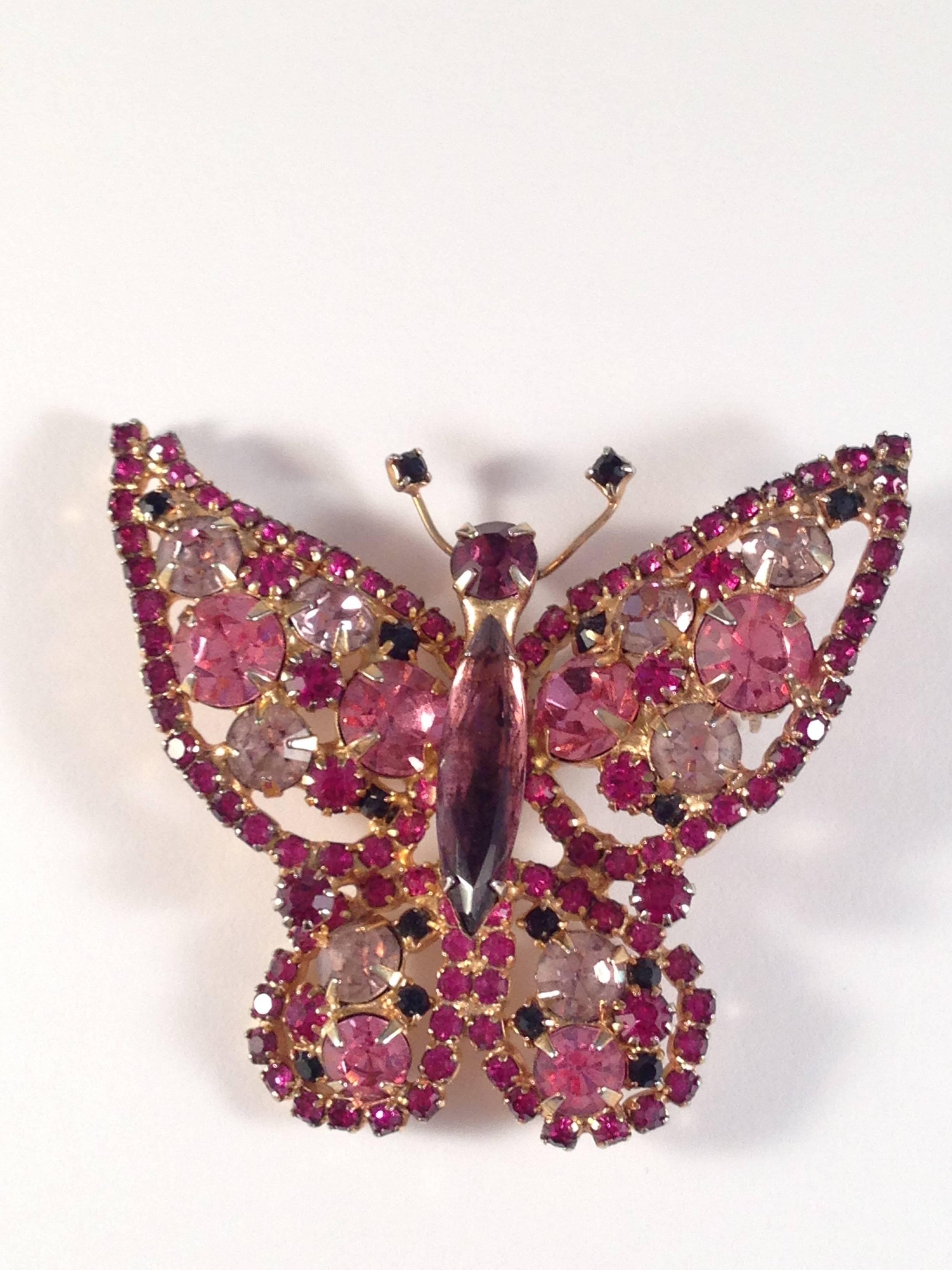 This is a beautiful signed Alice Caviness butterfly brooch. It is set in a gold toned setting and has pink, purple and lavender glass stones. It is signed 