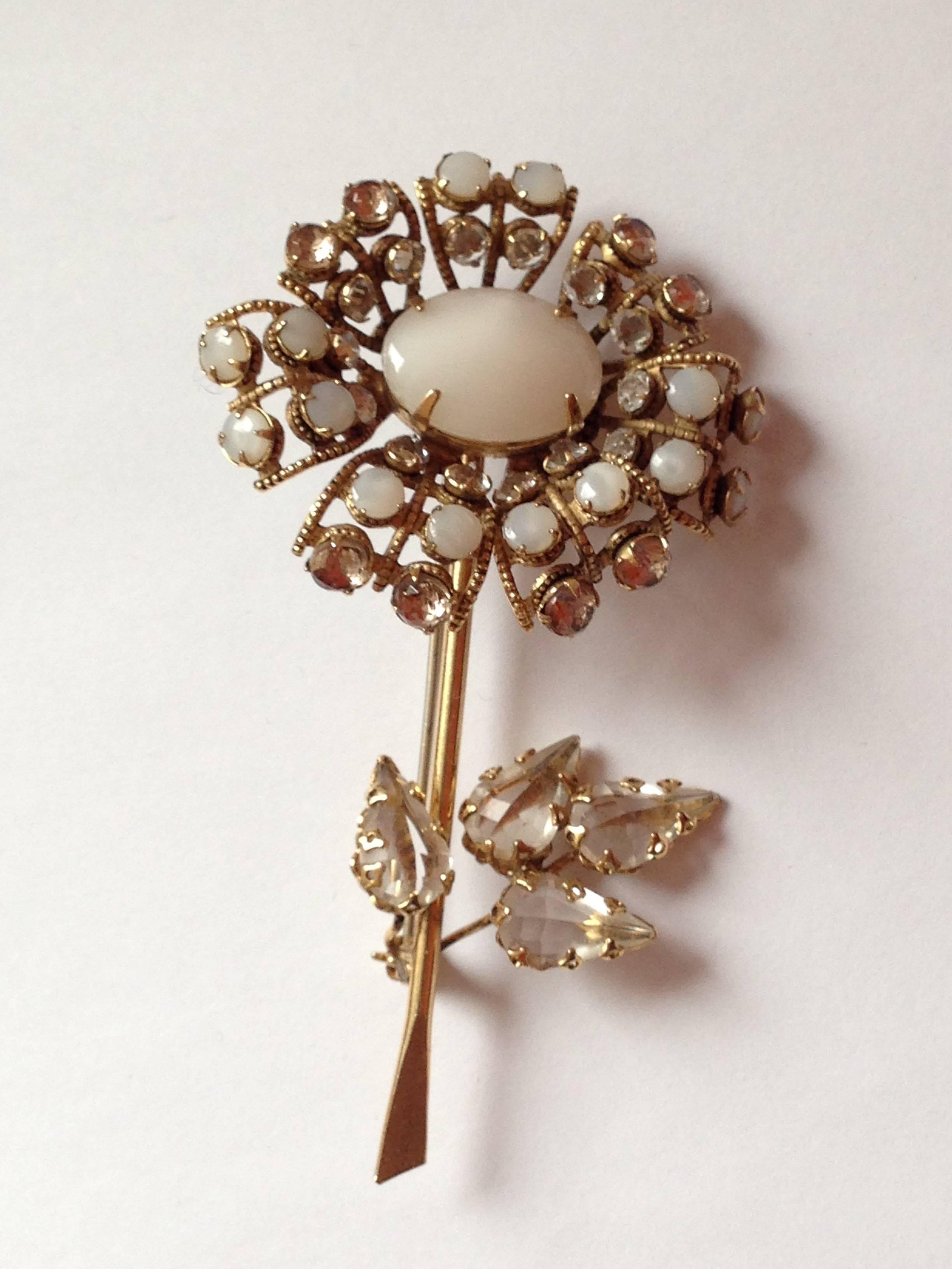 This 1950s Schreiner brooch is in the shape of a single flower. It features clear and opaque stones. The leaves are set with the pointed side out - a Schreiner signature. It is signed 'Schreiner New York' on a plaque on the back. It is 3 3/8