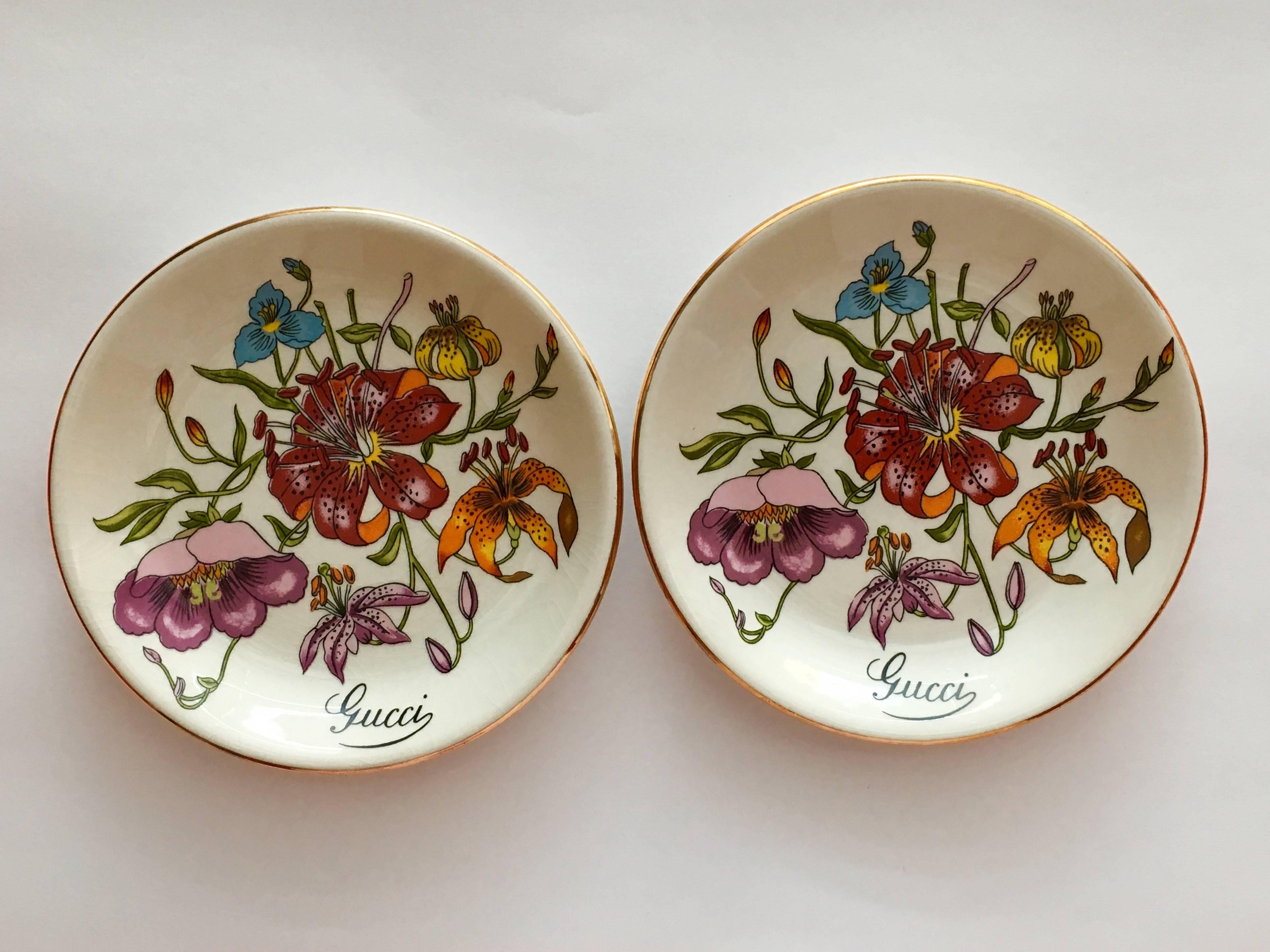 Vintage Gucci floral trinket or jewelry dishes. These dishes are decorated with multi-colored flowers and signed 'Gucci' on the front and 'Gucci Florence Made in England' in gold lettering on the backs. They are painted with gold around each rim and
