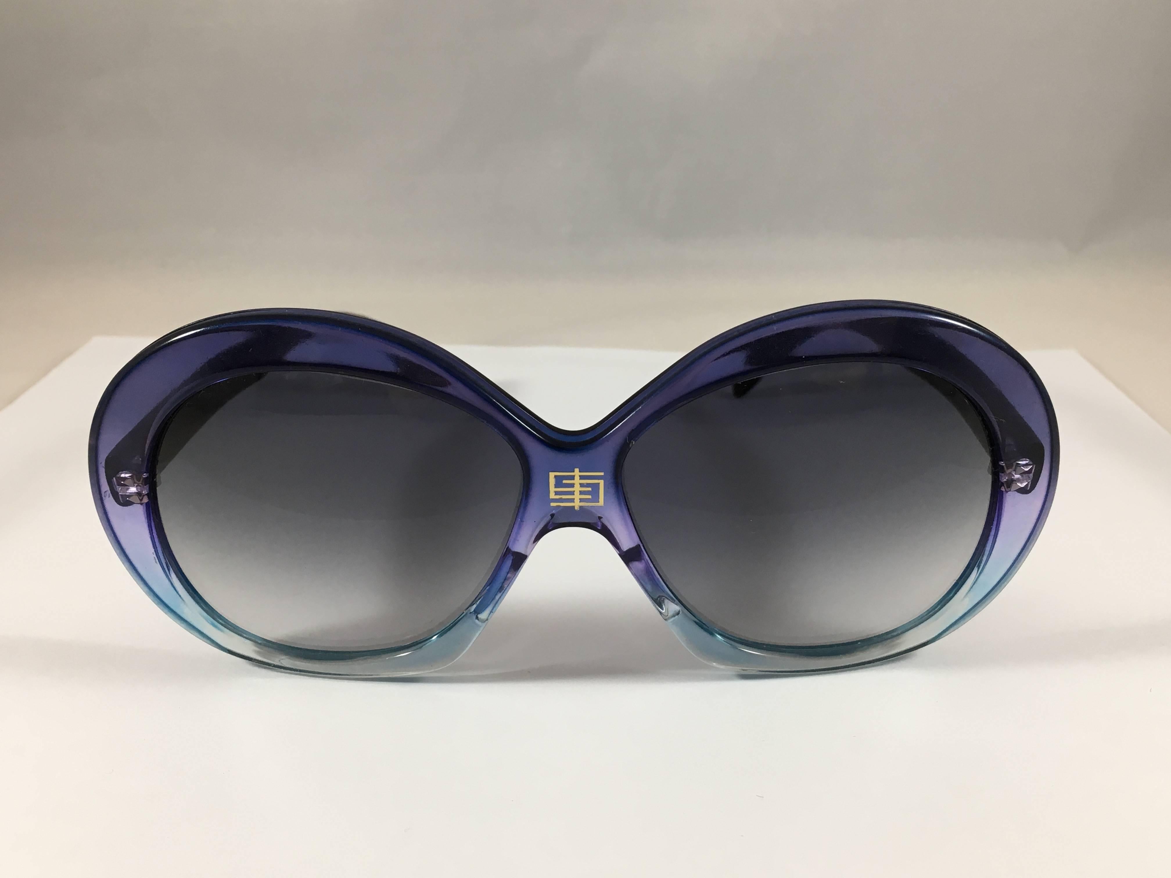 1970s Emilio Pucci blue ombre sunglasses with oversized round frames. On the center bridge of the frames there is a gold interlocking 'E' Pucci logo. Each arm of the glasses is marked with a gold 'Emilio Pucci'. One of the inside arms is marked