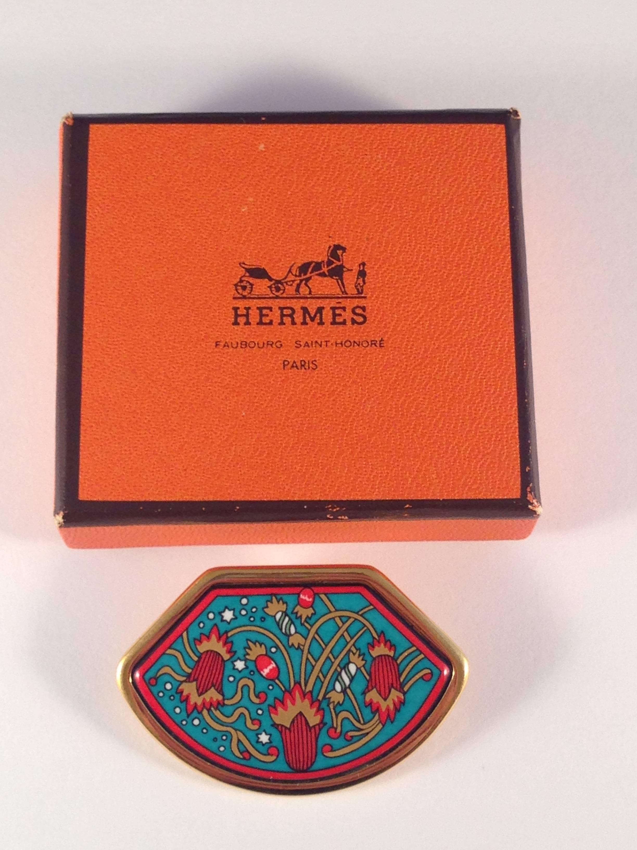 This is a 1990s Hermes gold-tone enamel brooch. Beautiful rich colors with an abstract floral pattern. It is in excellent condition. It is marked "Hermes Made in France" on the back and comes in its original box. It is 1 3/4" wide at