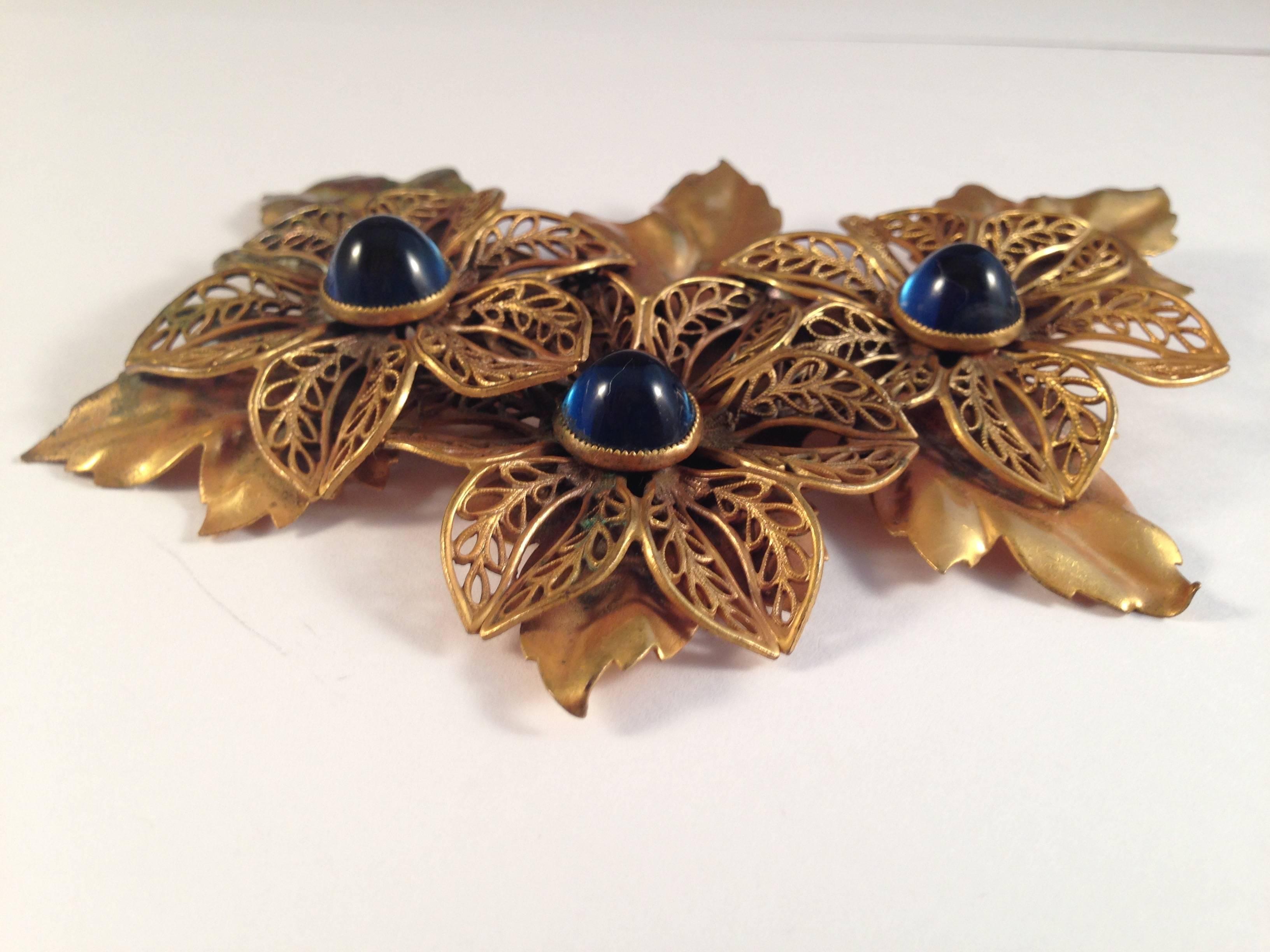 This is a large gold-tone 1940s Joseff of Hollywood brooch with blue glass floral centers.  It measures 4" long and 3" tall. The brooch is in good vintage condition. There is wear to the finish on the leaf on the upper right hand side of