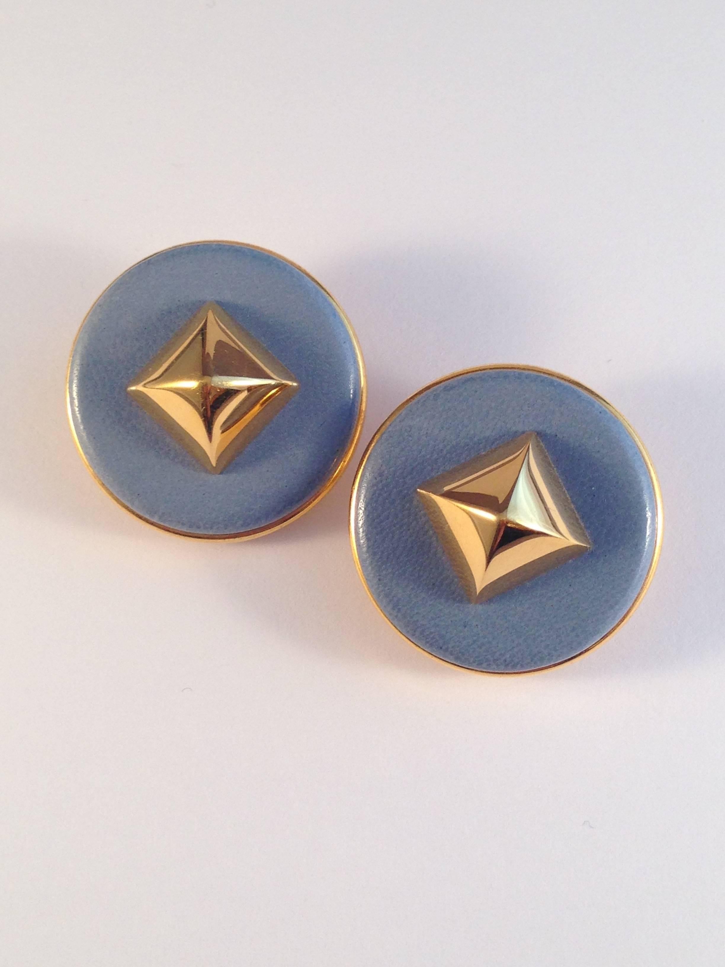 Vintage Hermes blue leather medor clip-on earrings. They measure 1 3/8" in diameter and are marked 'Hermes Paris' on the back. They are in excellent condition.