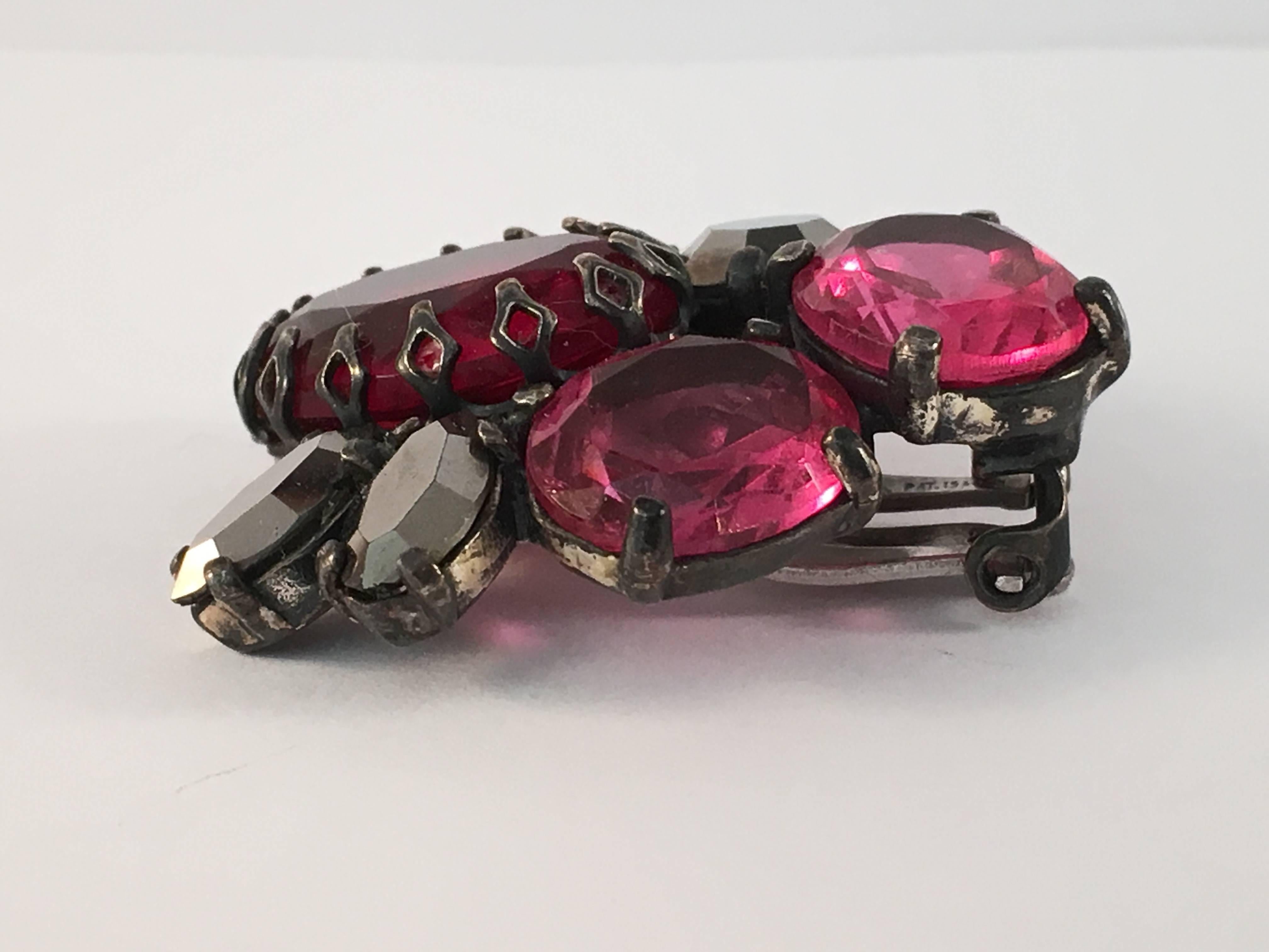 Iconic 1950s Schiaparelli pink clip-on earrings. These earrings measure 1 3/8" long x 1 1/4" wide and have prong set pink, red and gun-metal colored glass stones. Both earrings are signed, 'Schiaparelli' on the back of the clips. The clips