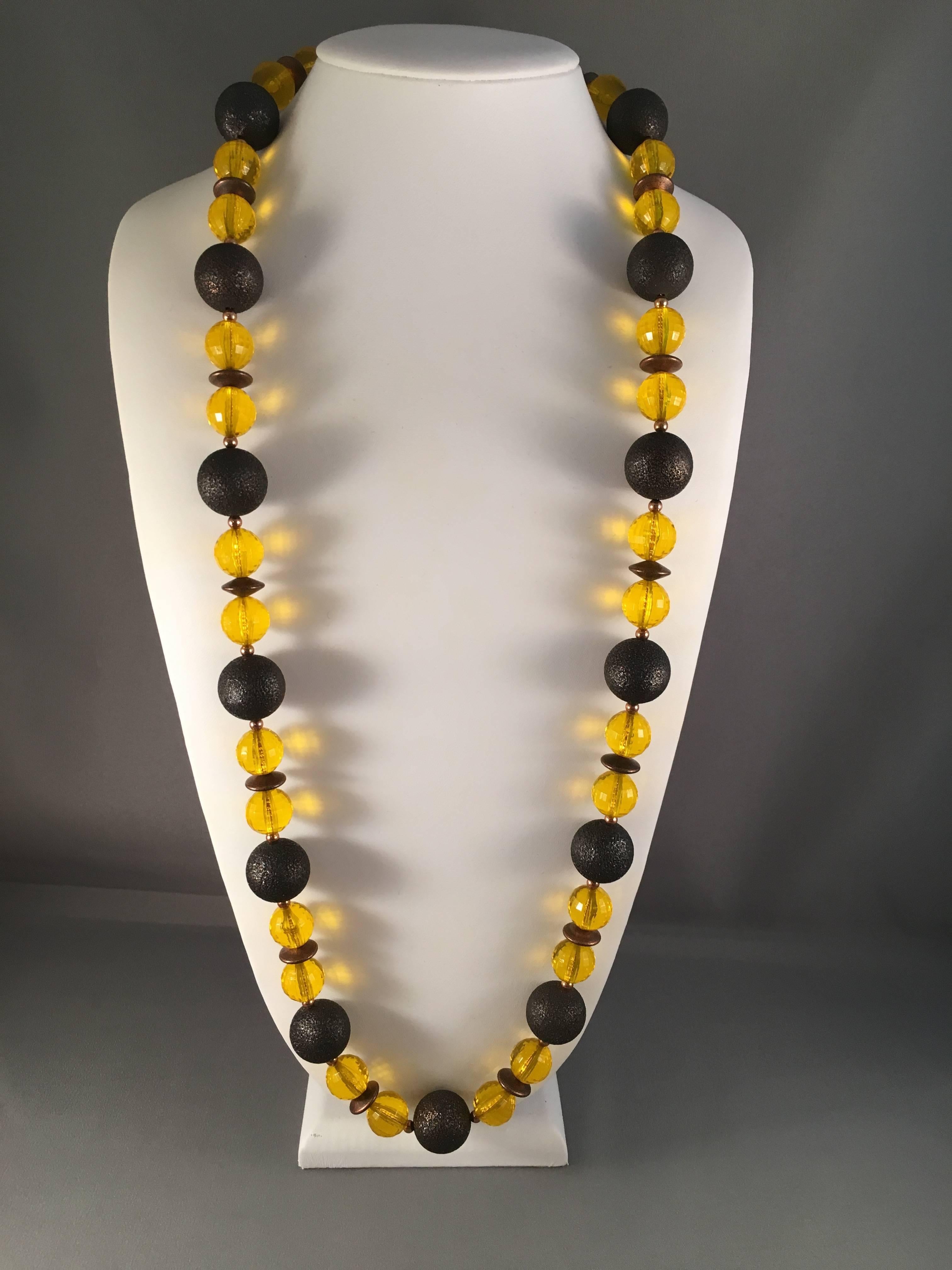 This is a 1970s Yves Saint Laurent metal and lucite beaded necklace. It features yellow faceted lucite and copper toned metal beads strung on a goldtone chain. The necklace measures 35" long and is in excellent condition. The closure features a