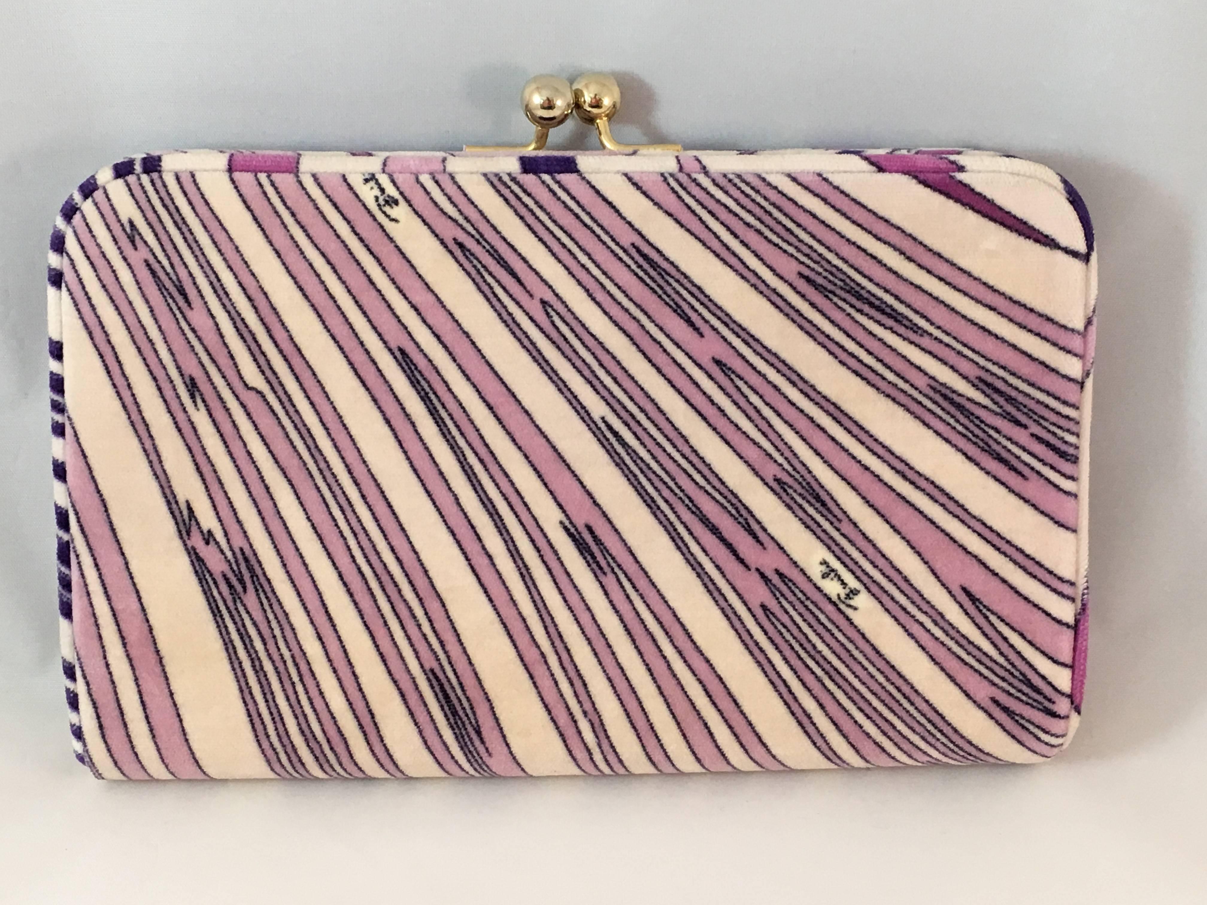 Gorgeous Pucci printed velvet clutch from the 1960's in excellent condition. All-over geometric print in shades of lilac and pink. The interior is lined in black satin. It closes with a snap closure at the top which is made up of two gold-toned