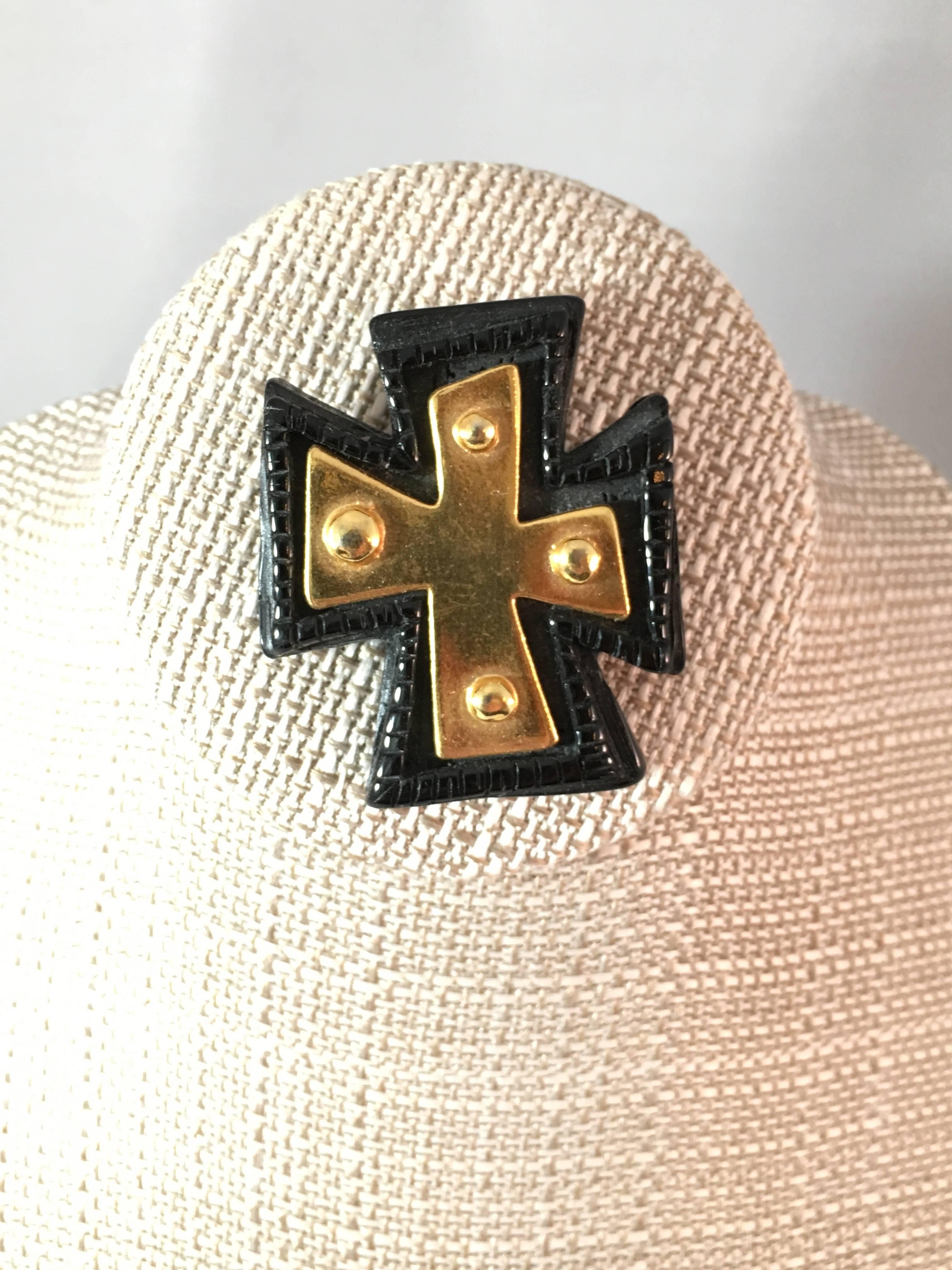 This 1980s Christian Lacroix cross brooch illustrates the designer's love of the cross as an iconic image. It is made out of black resin with a gold-tone resin cross in the center. It measures 2