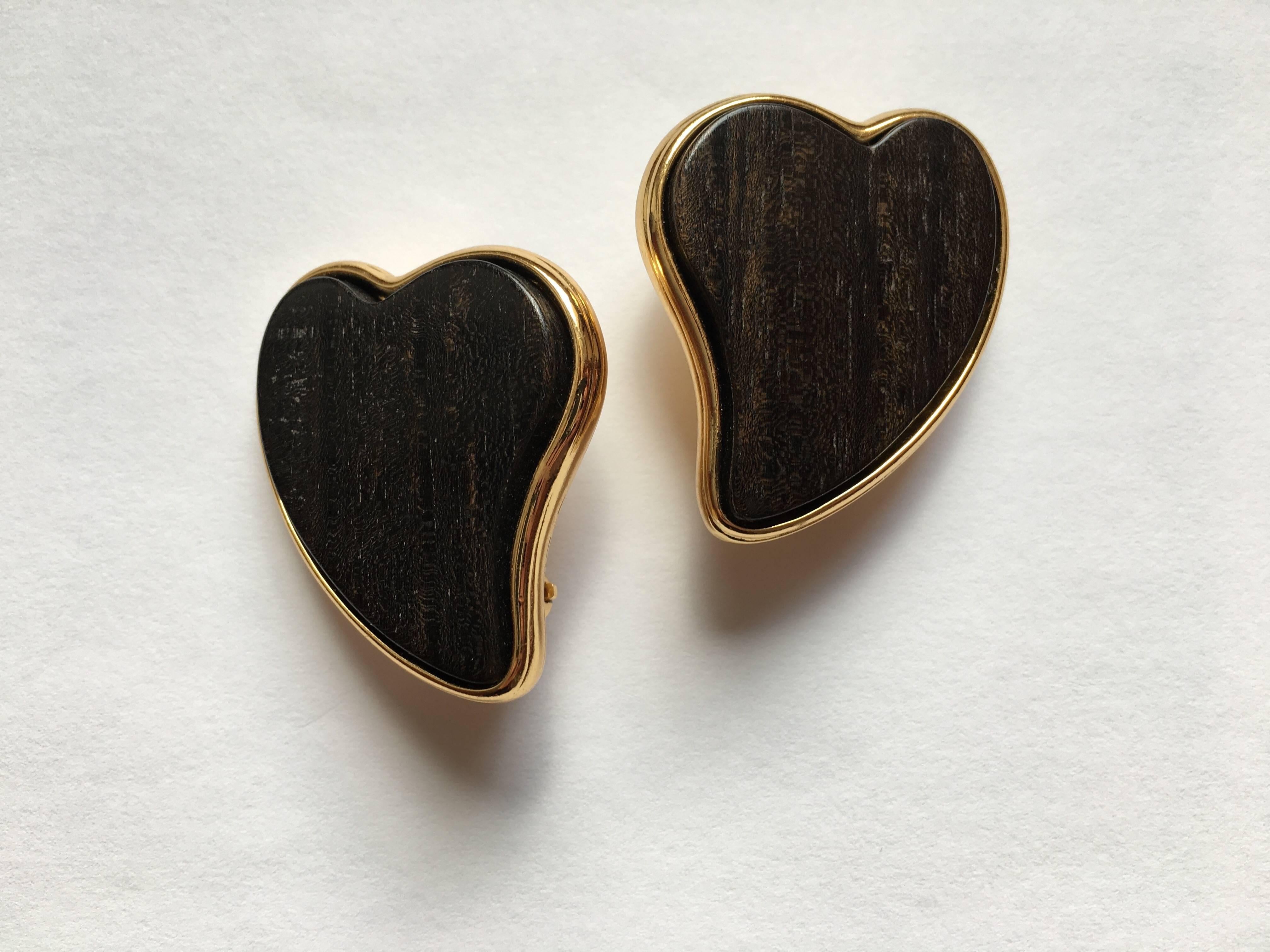 This is a gorgeous pair of Yves Saint Laurent 1980s heart-shaped clip-on earrings in gold-tone metal set with wooden hearts. They are marked on the back of the clips with 