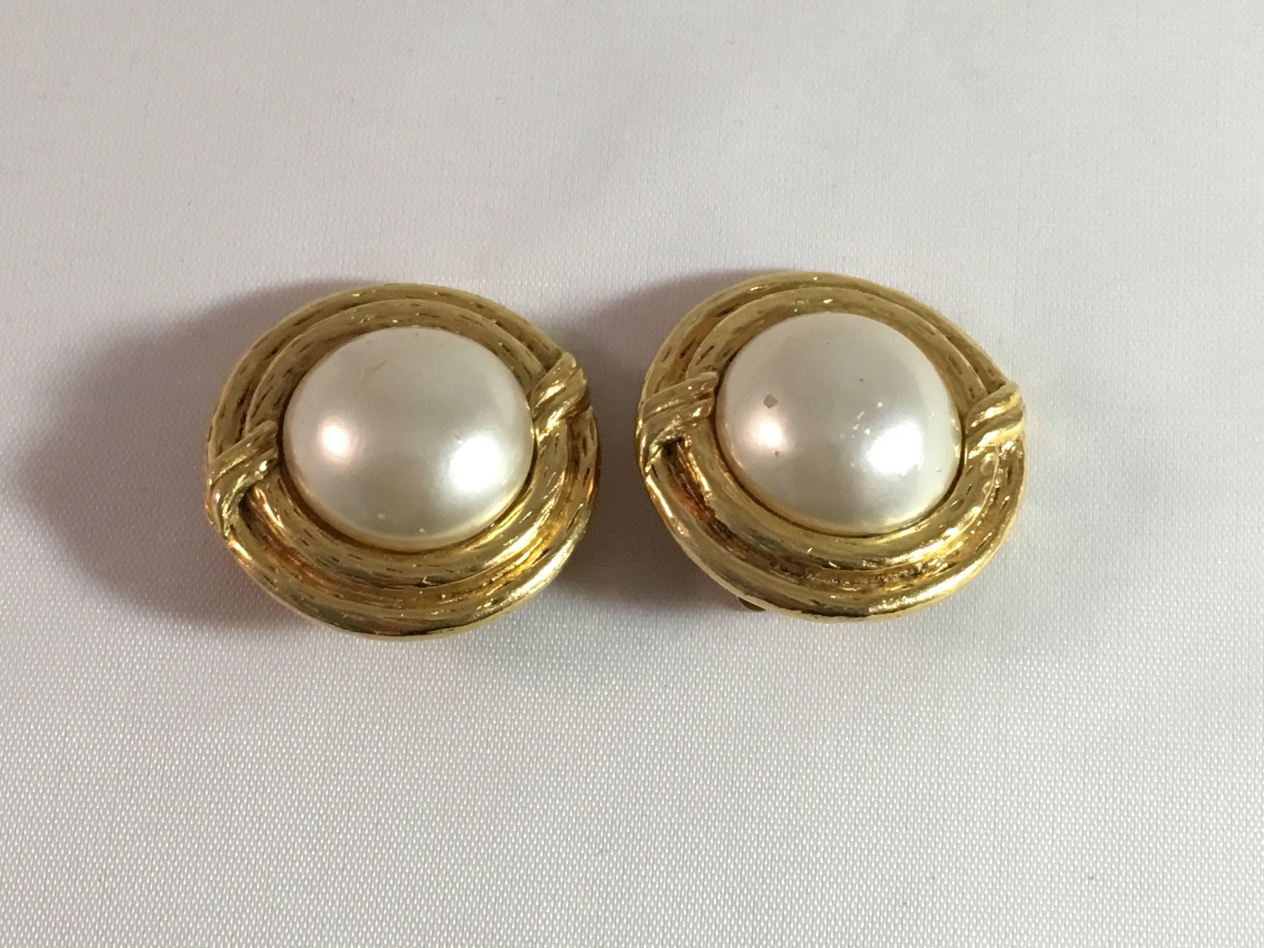 Beautifully made, early 1980's or late 1970s Chanel pearl and goldtone clip-on earrings. They feature a large faux pearl in the center and are signed on the back with a mark indicating (see image 3) that they date to the late 1970s or early 1980s.