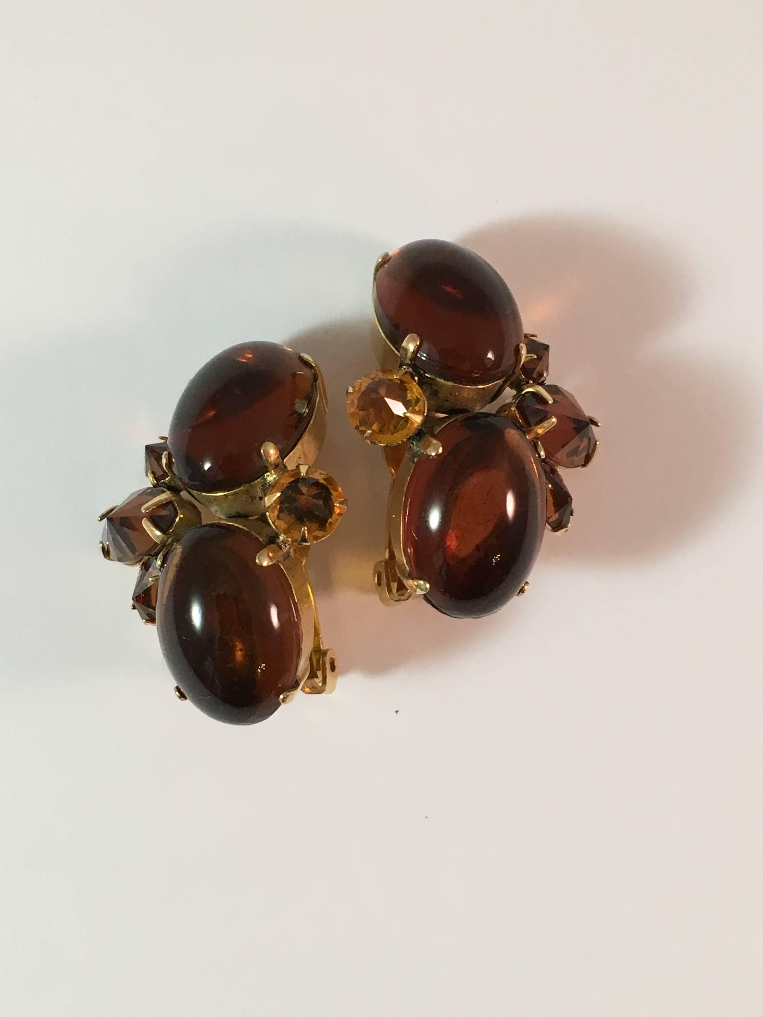 This is a beautiful pair of 1950s Schreiner clip-on earrings. They are gold-toned metal set with brown and dark yellow glass crystals. The two side baguettes on each earring are set with the pointed side up - a Schreiner trademark. They measure 1