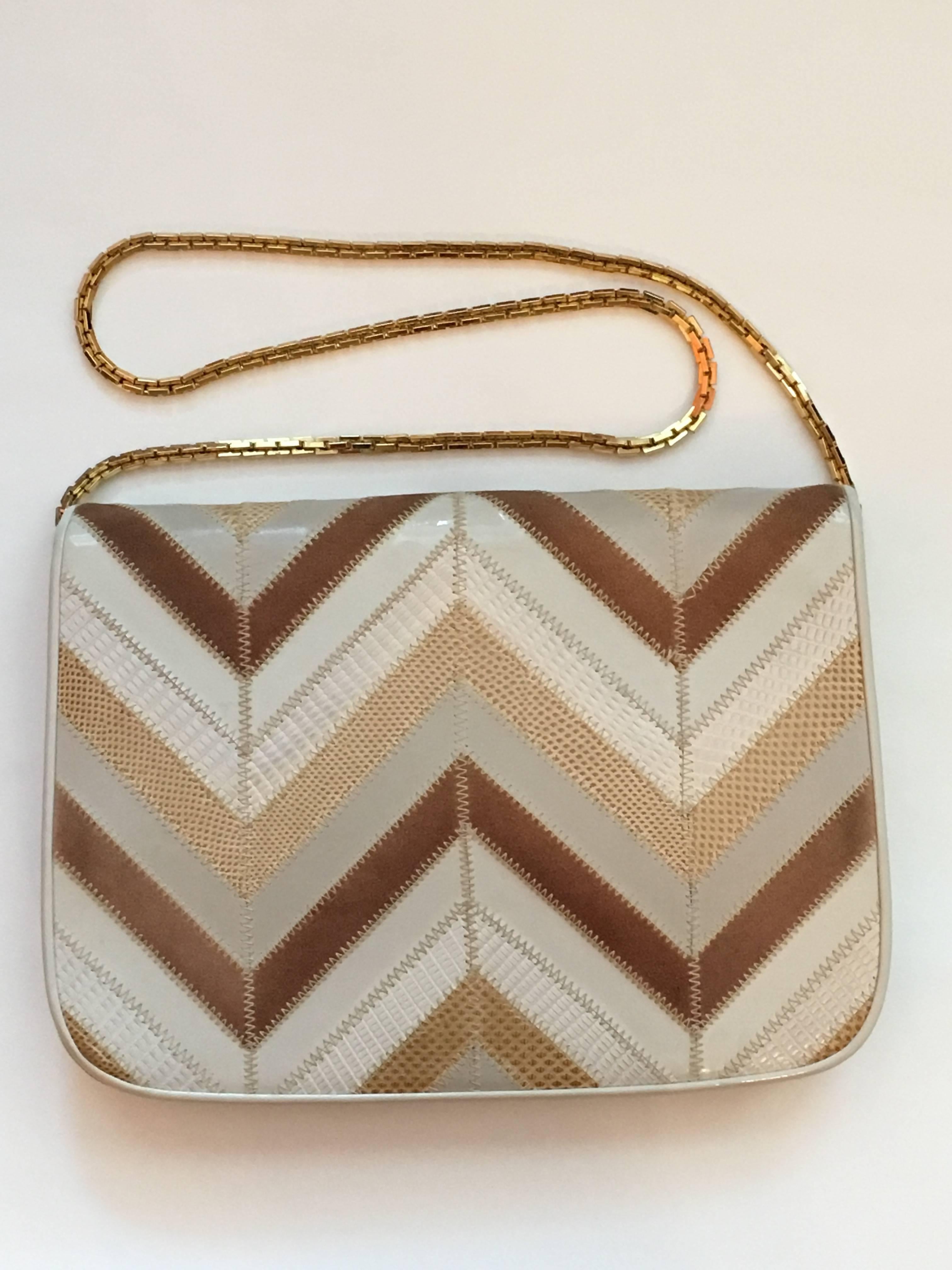 This is a fabulous 1970s Judith Leiber zig zag patchwork clutch made up of snake skins, suede, leather and patent leather. It can be used as a clutch or the removable gold chain can be attached and it can be used as a shoulder bag. It measures 9