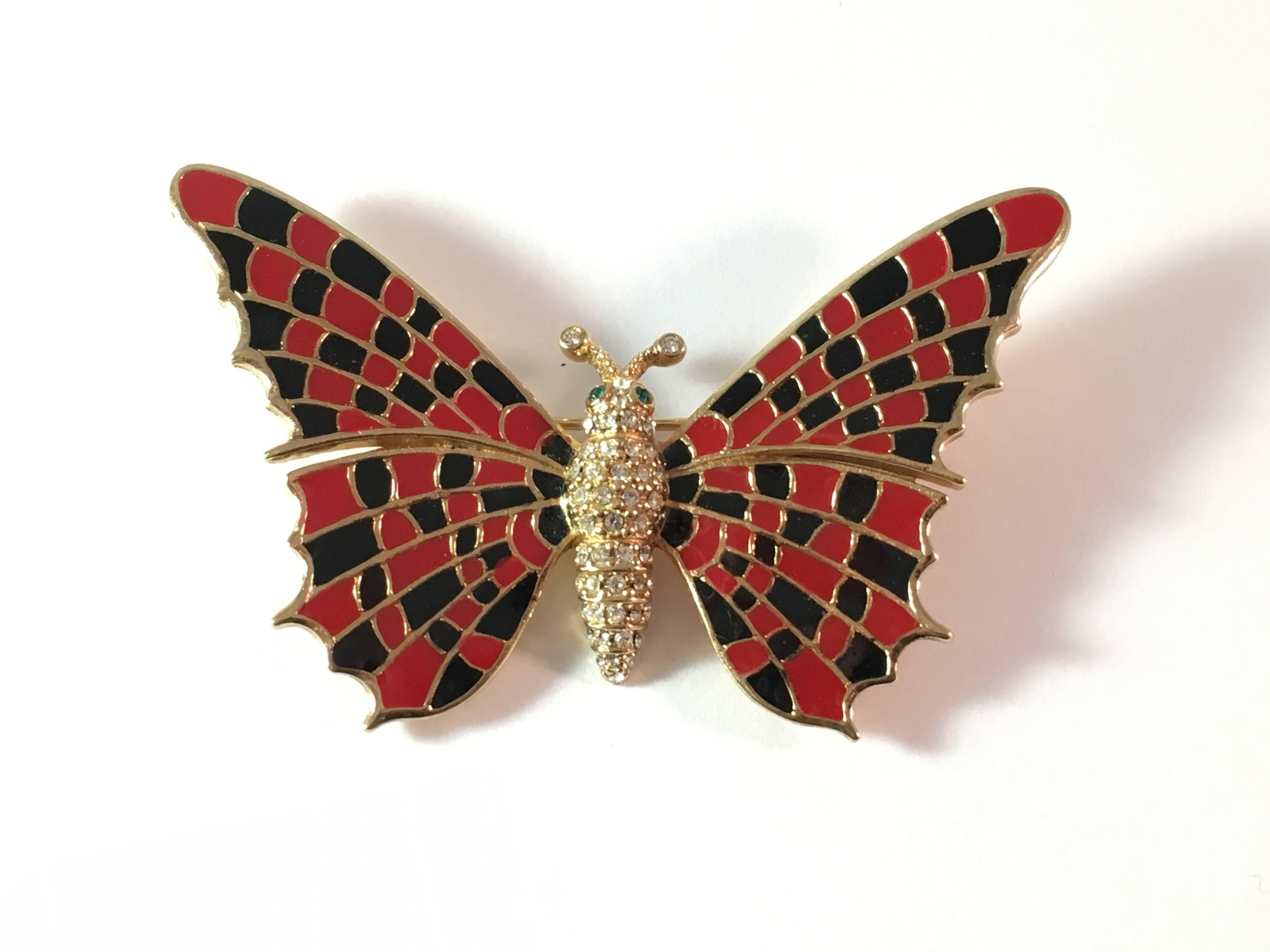 This is a stunning butterfly brooch from Ciner. Its wings are made up of red and black enamel. The butterfly's body is made up of clear pave rhinestones with green rhinestone eyes. The back of the brooch is marked 'Ciner' and it measures 2 3/4"