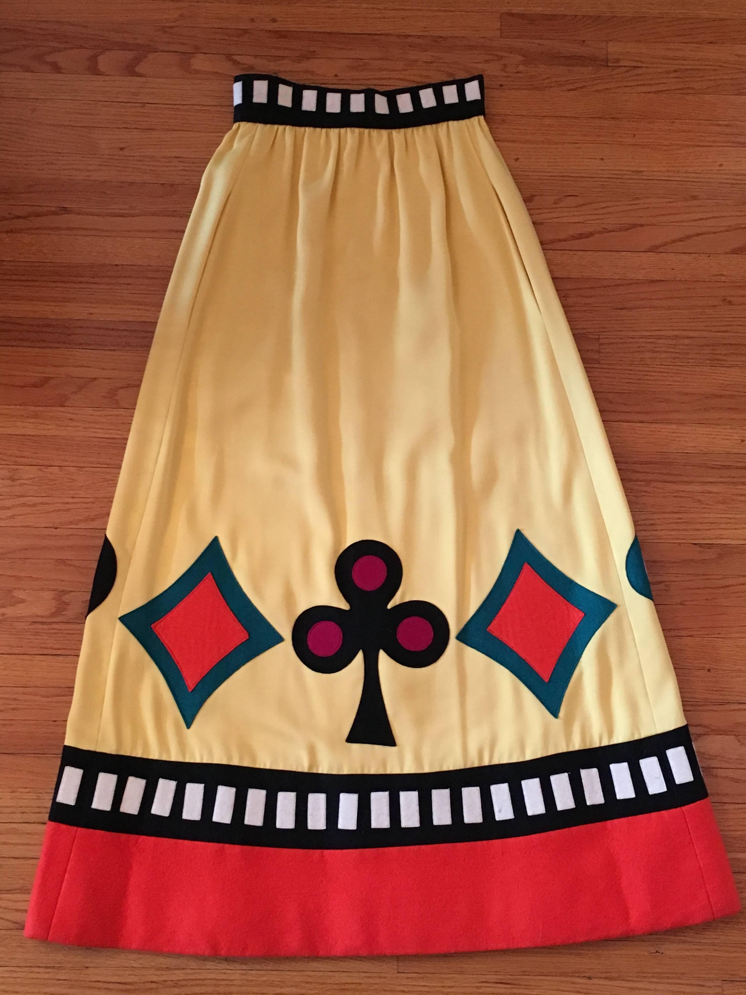 Youssef Rizkallah designed this amazing skirt for Malcolm Starr in the 1970s. He designed for Malcolm Starr from 1969 - 1975. The skirt is a long yellow sateen maxi skirt that zips up the back. The waistband is trimmed with with black and white felt