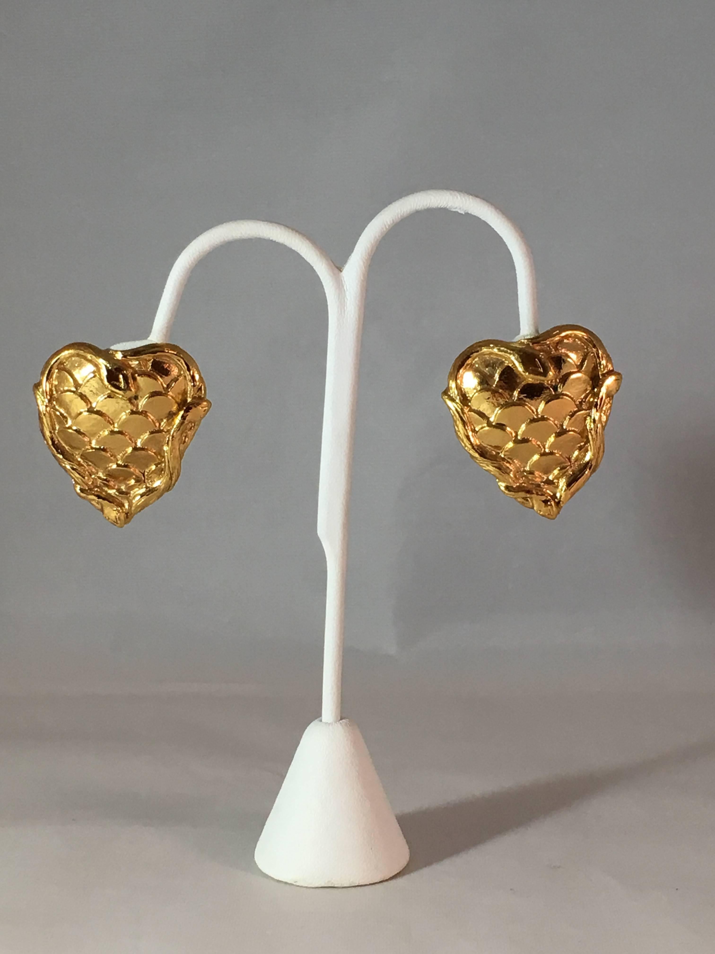 These fabulous goldtone Yves Saint Laurent heart clip-on earrings feature a snakeskin pattern in the center and are surrounded on the edges by snakes. Snakes and hearts were commonly used symbols by Yves Saint Laurent. The earrings are marked YSL on
