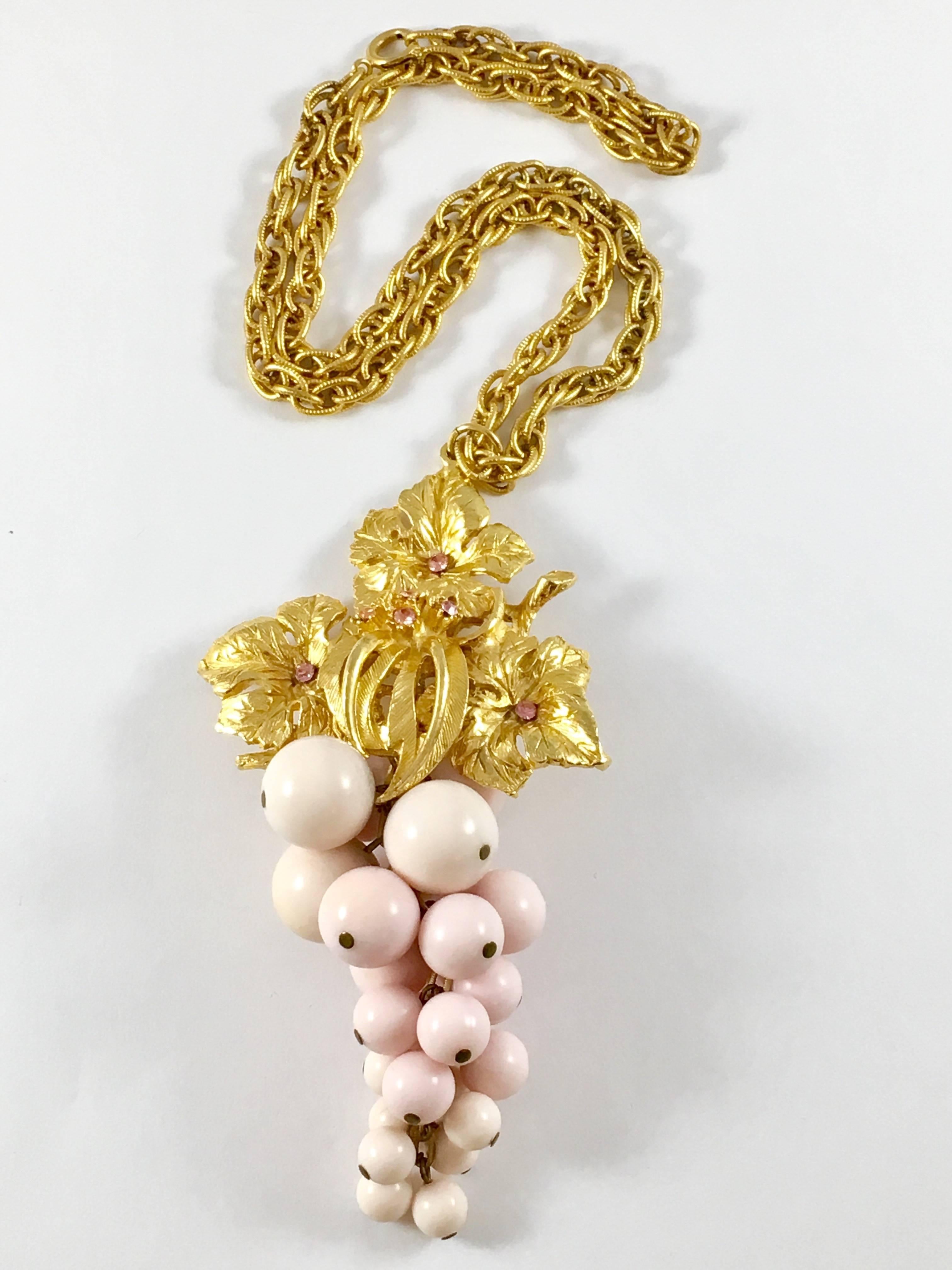 This is a fabulous, really fun 1950s grape pendant necklace made by Alice Caviness. The grapes are made out of resin and are a pale pink color. The grape leaves are gold-toned with pink rhinestones. The pendant measures 5 inches long and 2 1/2