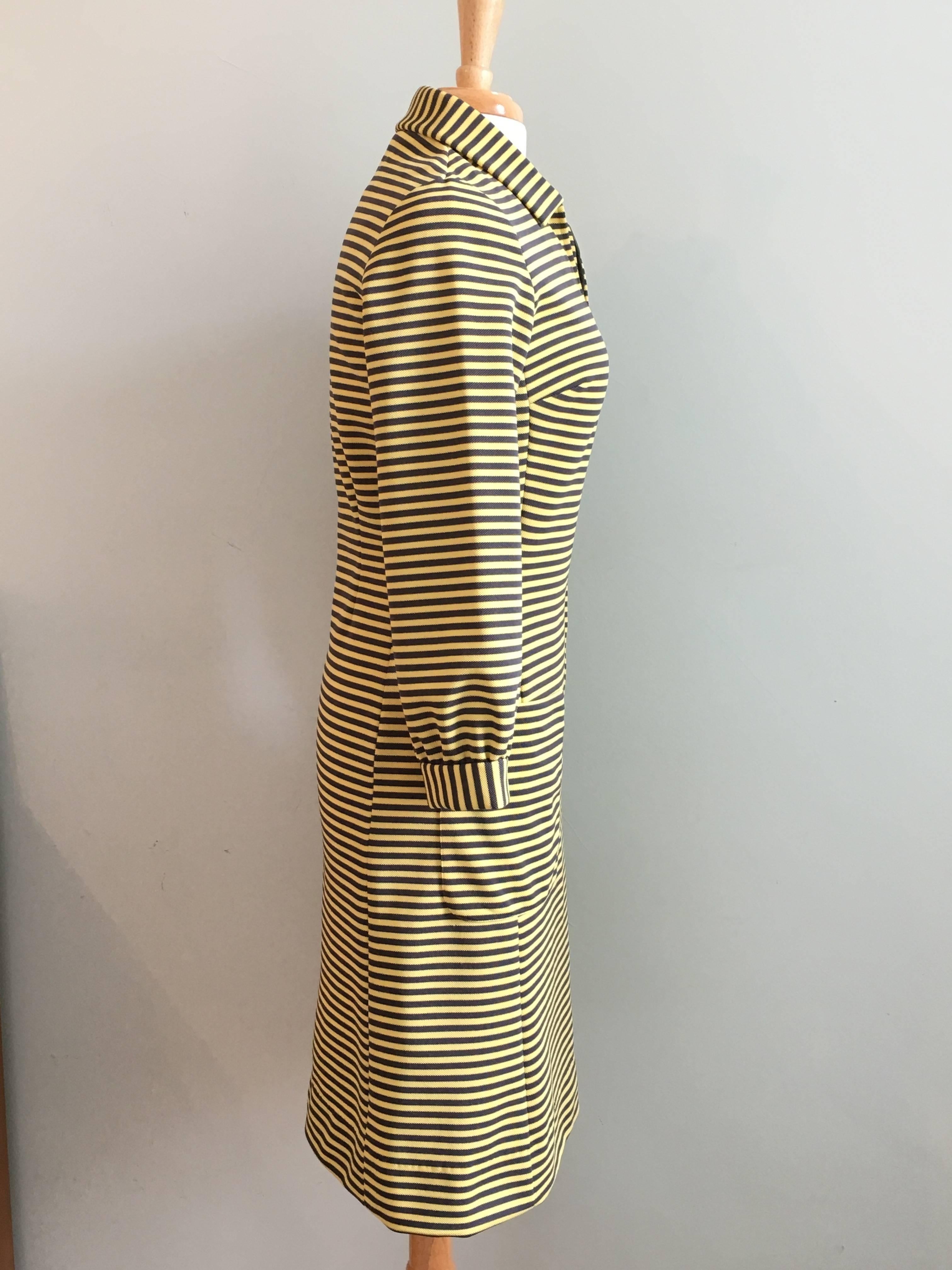 This is a 1970s yellow and grey knit striped dress from Chemise Lacoste. It zips up the front and has two patch pockets. It is in excellent condition and looks as if it was never worn. There is a signature embroidered alligator on the left front